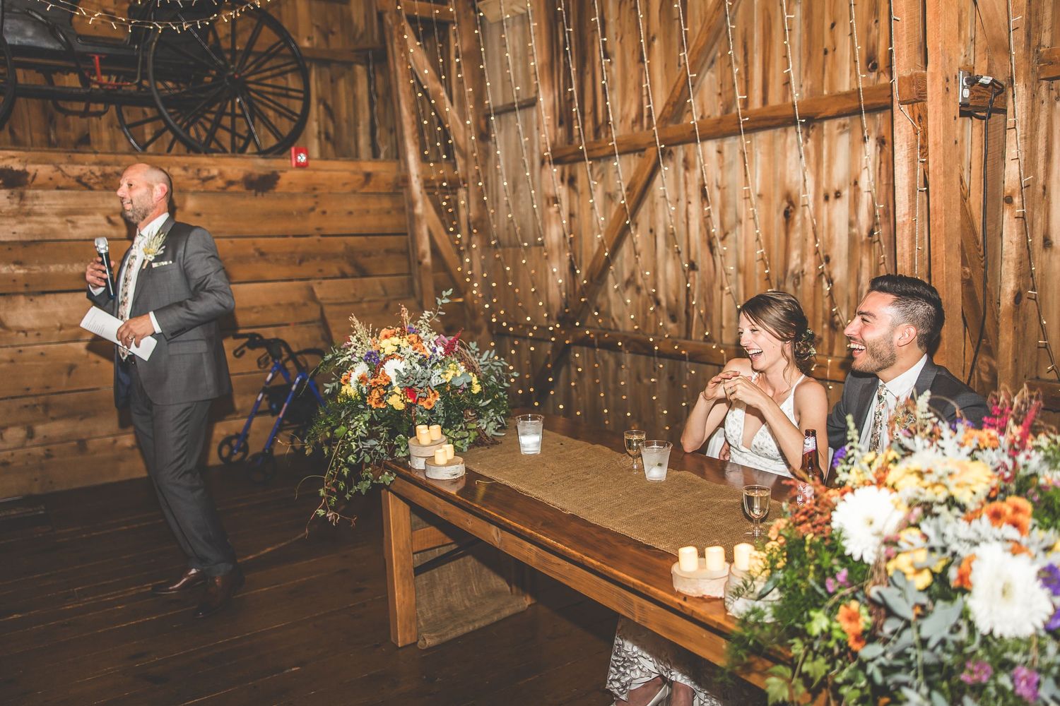 Rustic barn wedding reception with wooden beams and elegant floral table decorations.