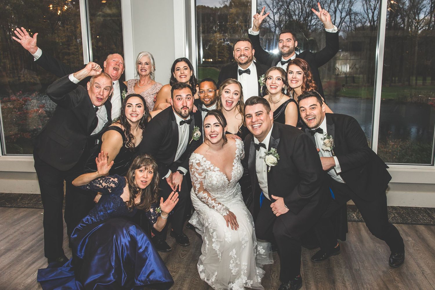 Wedding reception guests pose enthusiastically for a group photo in an elegant venue.
