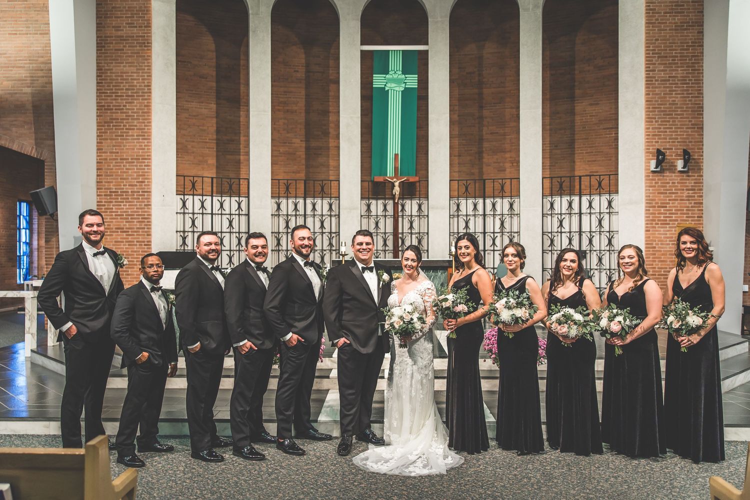 Wedding party lined up outside church with classic brick and column architecture.