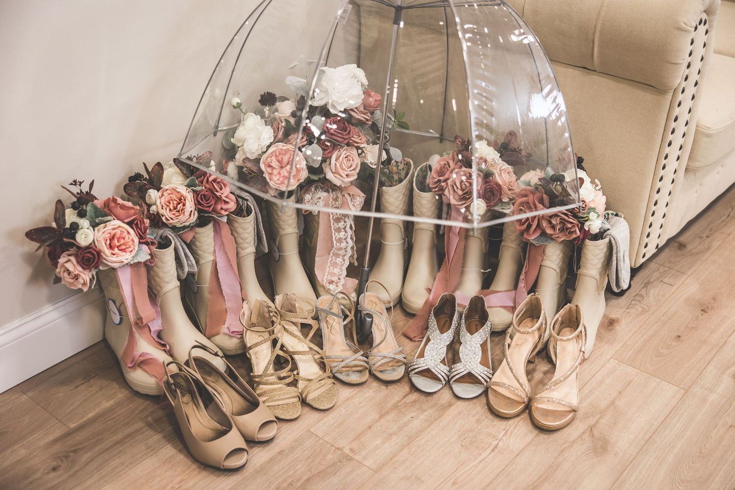 Collection of pink and beige bridesmaid shoes lined up on a light colored floor.