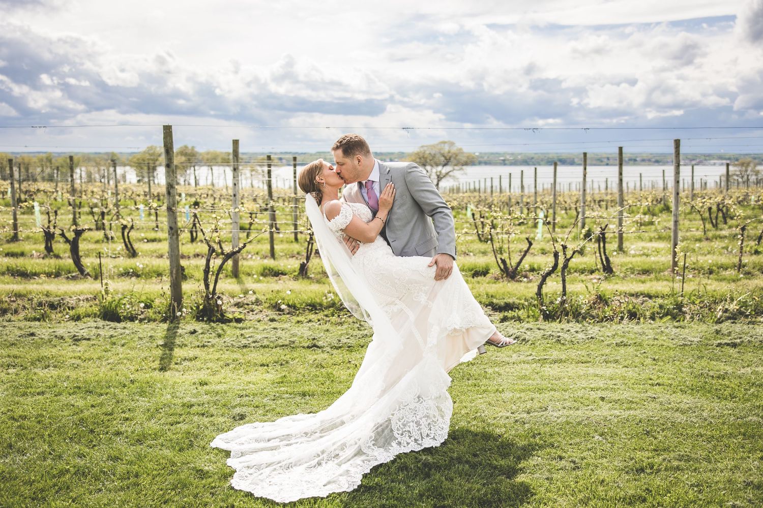 Elegant bridal portraits showcasing a flowing veil and dress in a vineyard landscape.