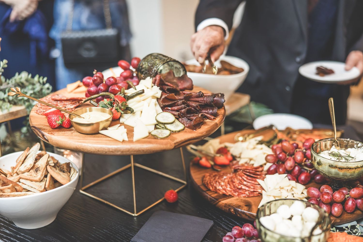 Tiered display of gourmet appetizers featuring meats, cheeses and fruits at wedding reception.