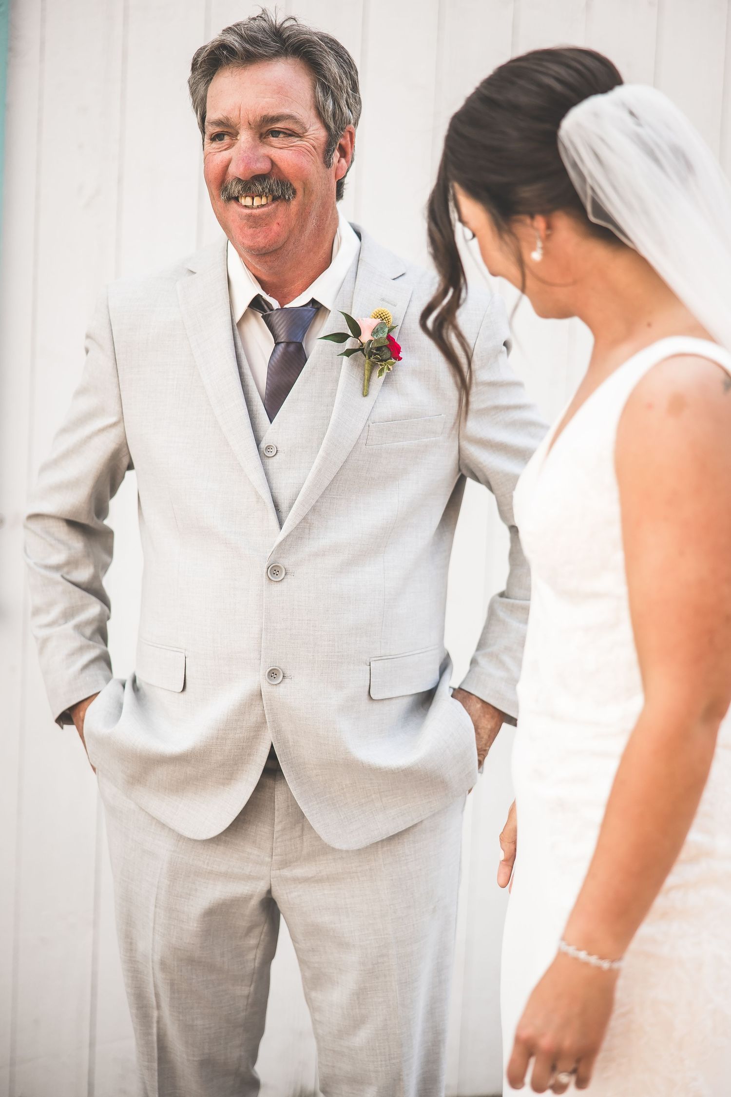 Wedding couple shares a tender moment in white and grey formal attire.