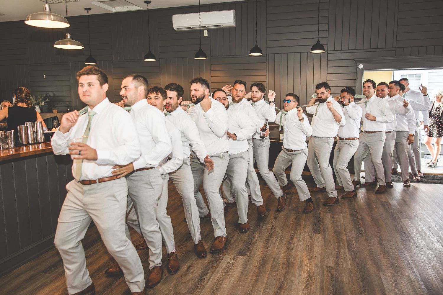 Wedding party performing choreographed dance routine in a rustic indoor venue.
