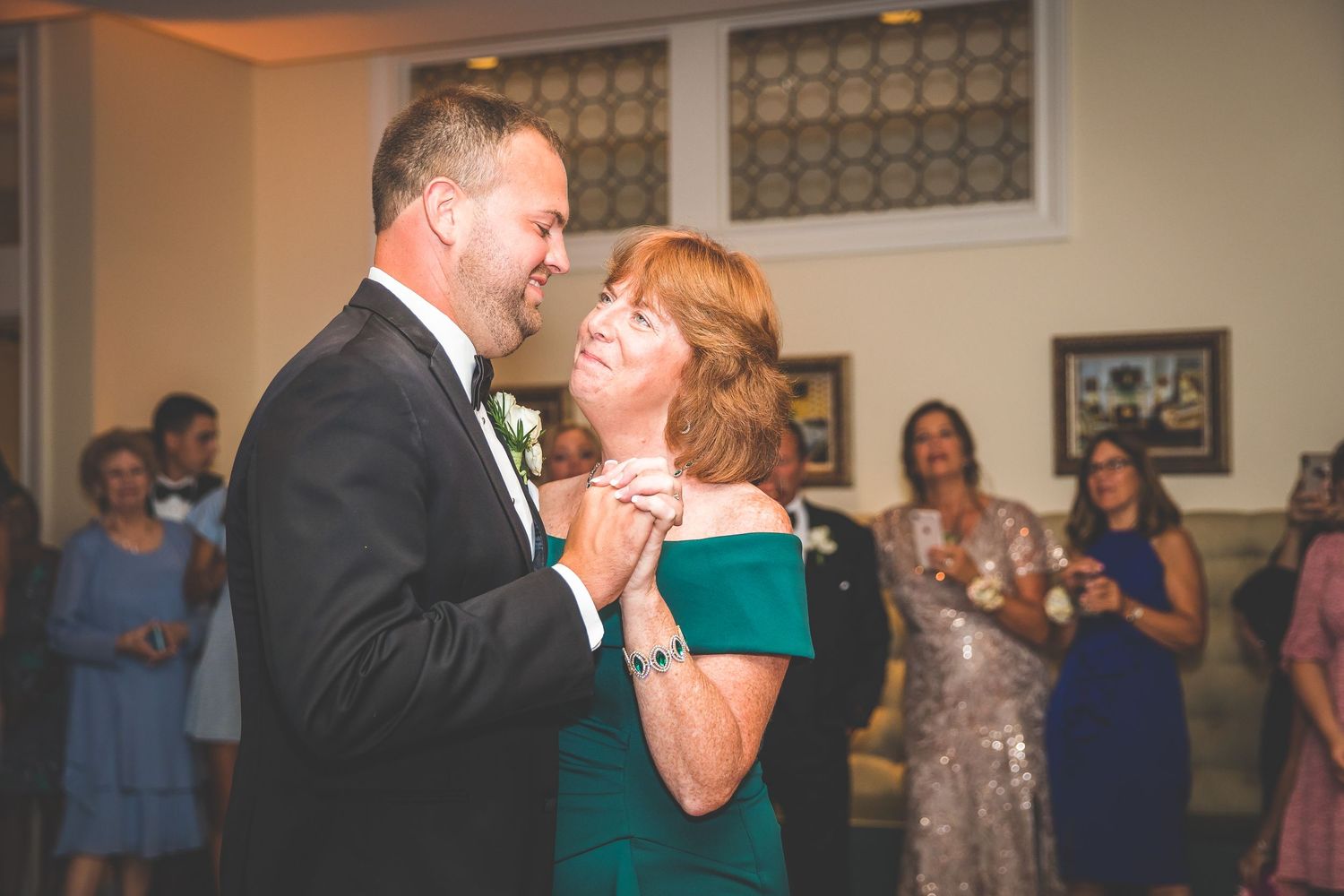 Couple embracing during their first dance at an indoor wedding venue.