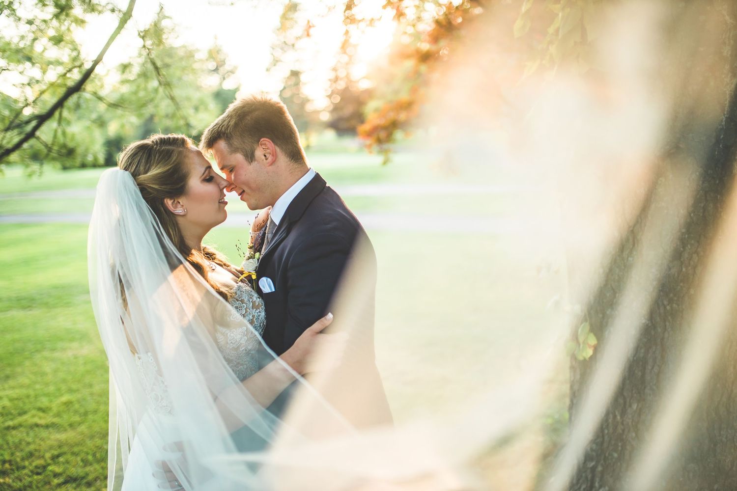 Wedding couple embraces during golden hour sunset in an outdoor garden setting.