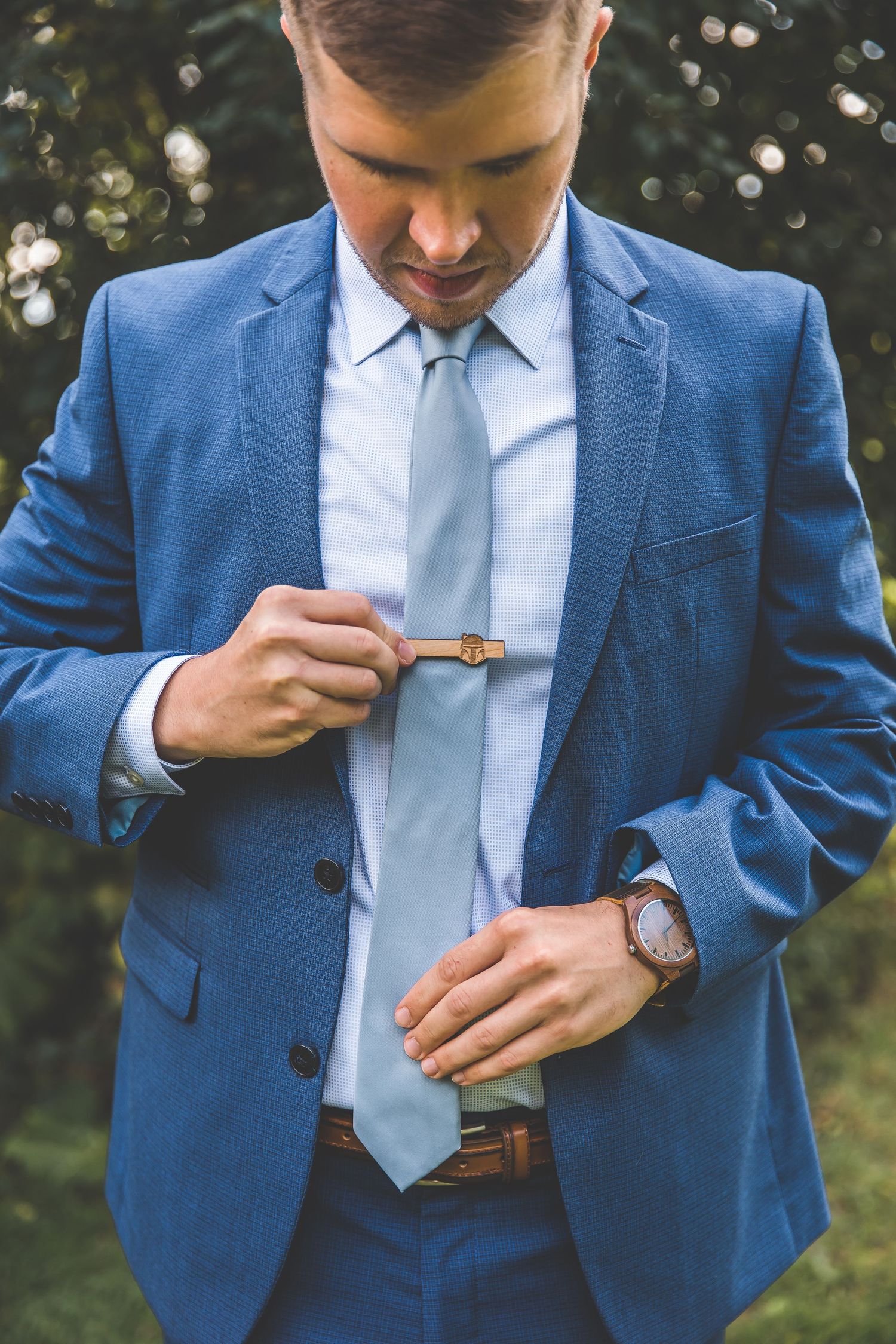 Detail shots of groom in blue suit adjusting cufflinks and accessories.