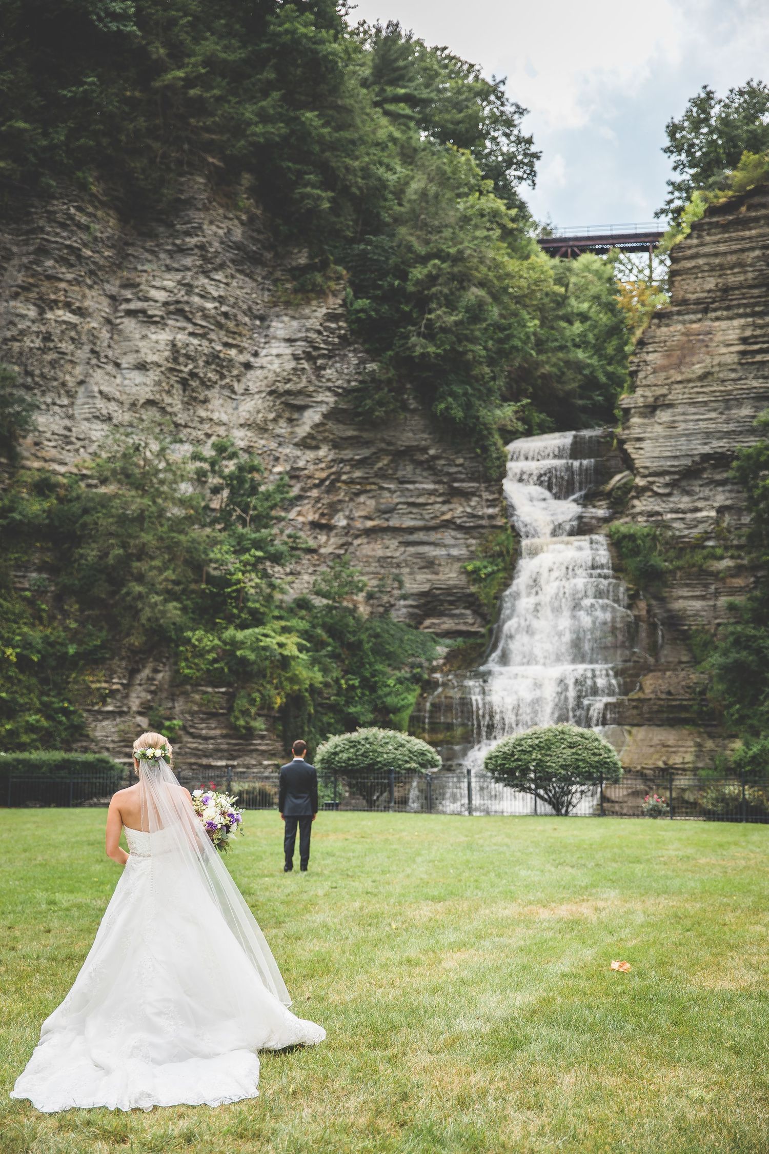 Wedding photos taken in front of a stunning natural waterfall and rock formation.