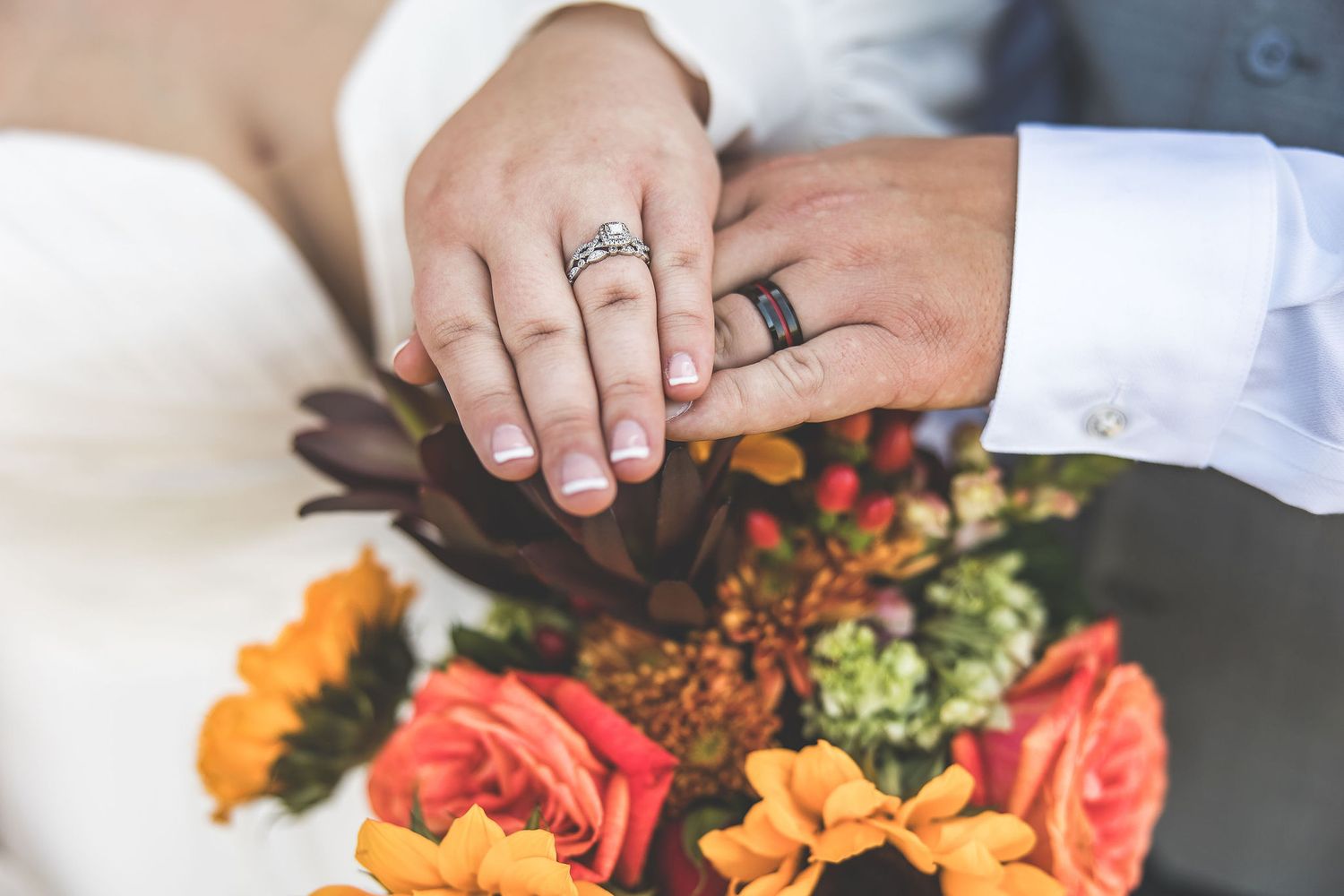 Close-up details of orange and red autumn wedding flower arrangements being assembled.