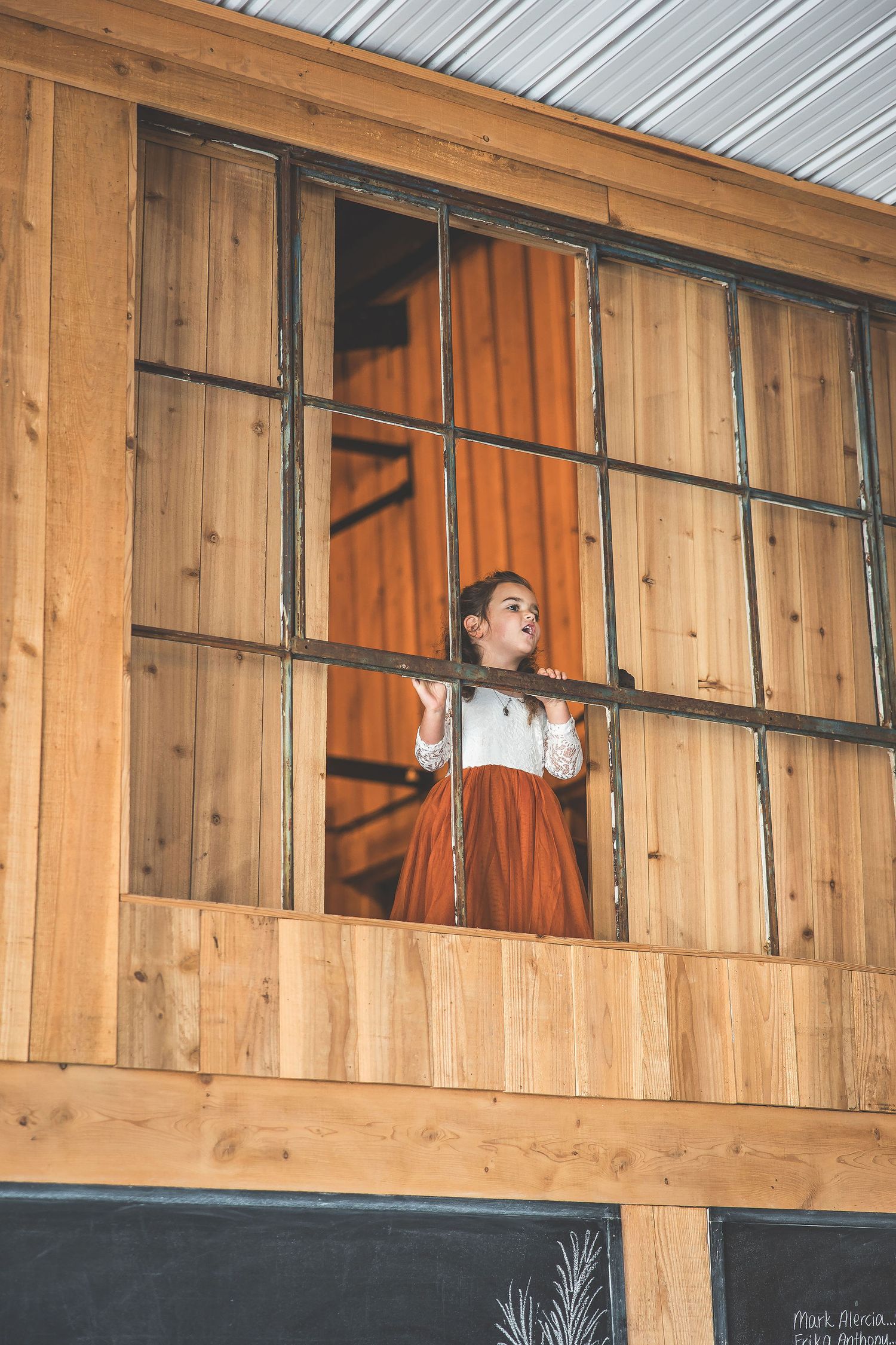 Interior view of a rustic wooden barn venue with large windows and natural lighting.
