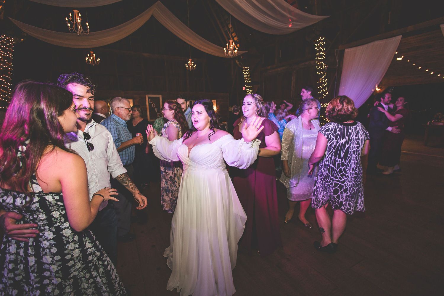 Lively dance floor scene at a wedding reception with guests in formal attire.
