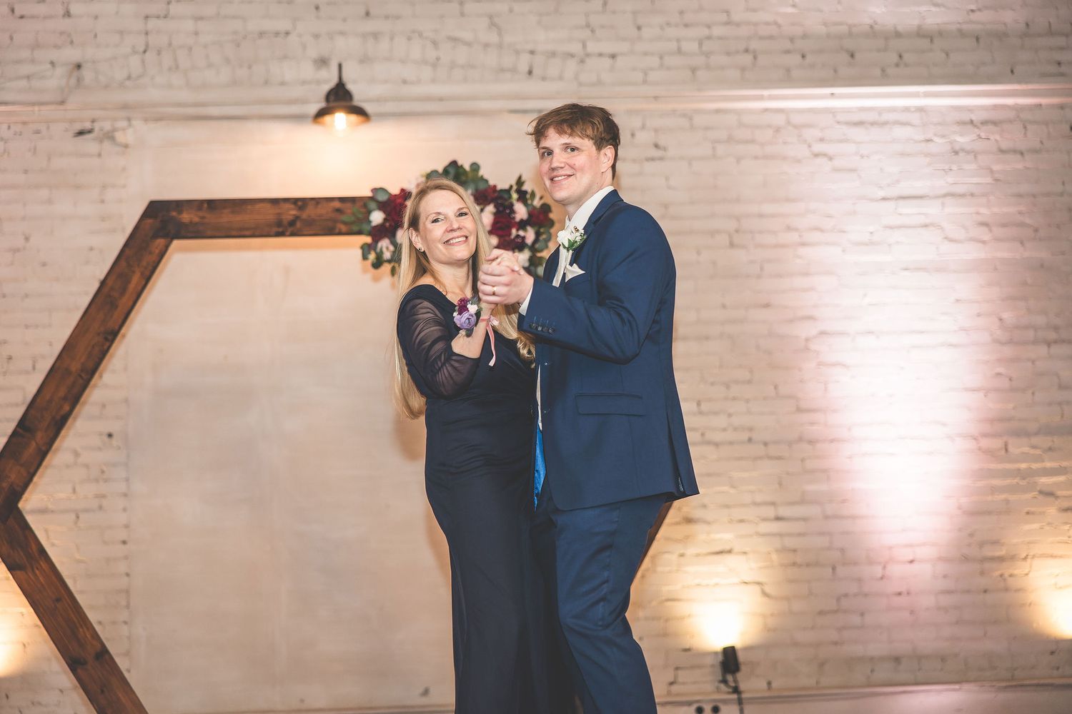 A couple dancing together under warm lighting at an indoor wedding reception.