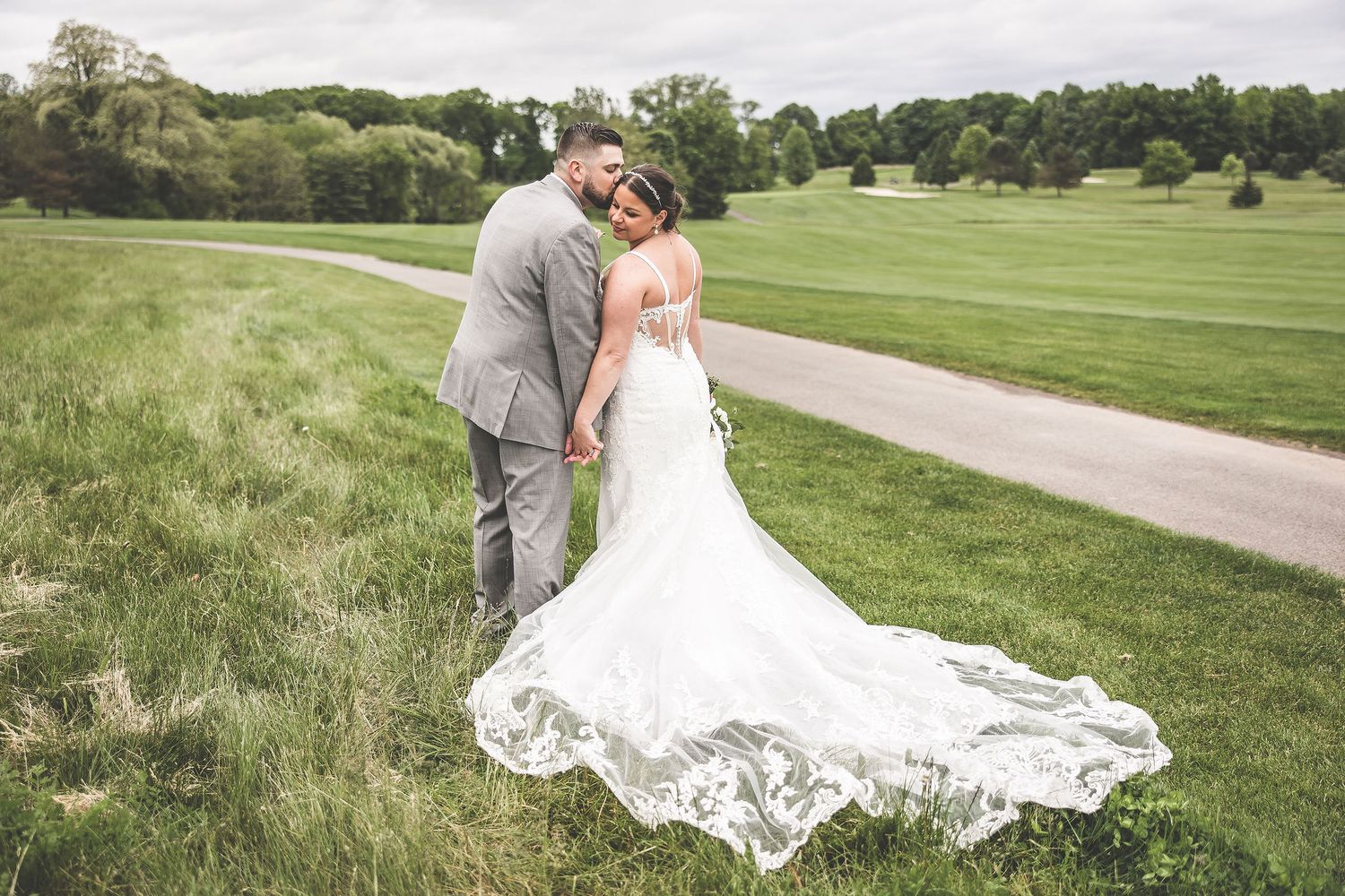 A series of wedding photos showcasing a beautiful lace dress train against a green outdoor landscape.