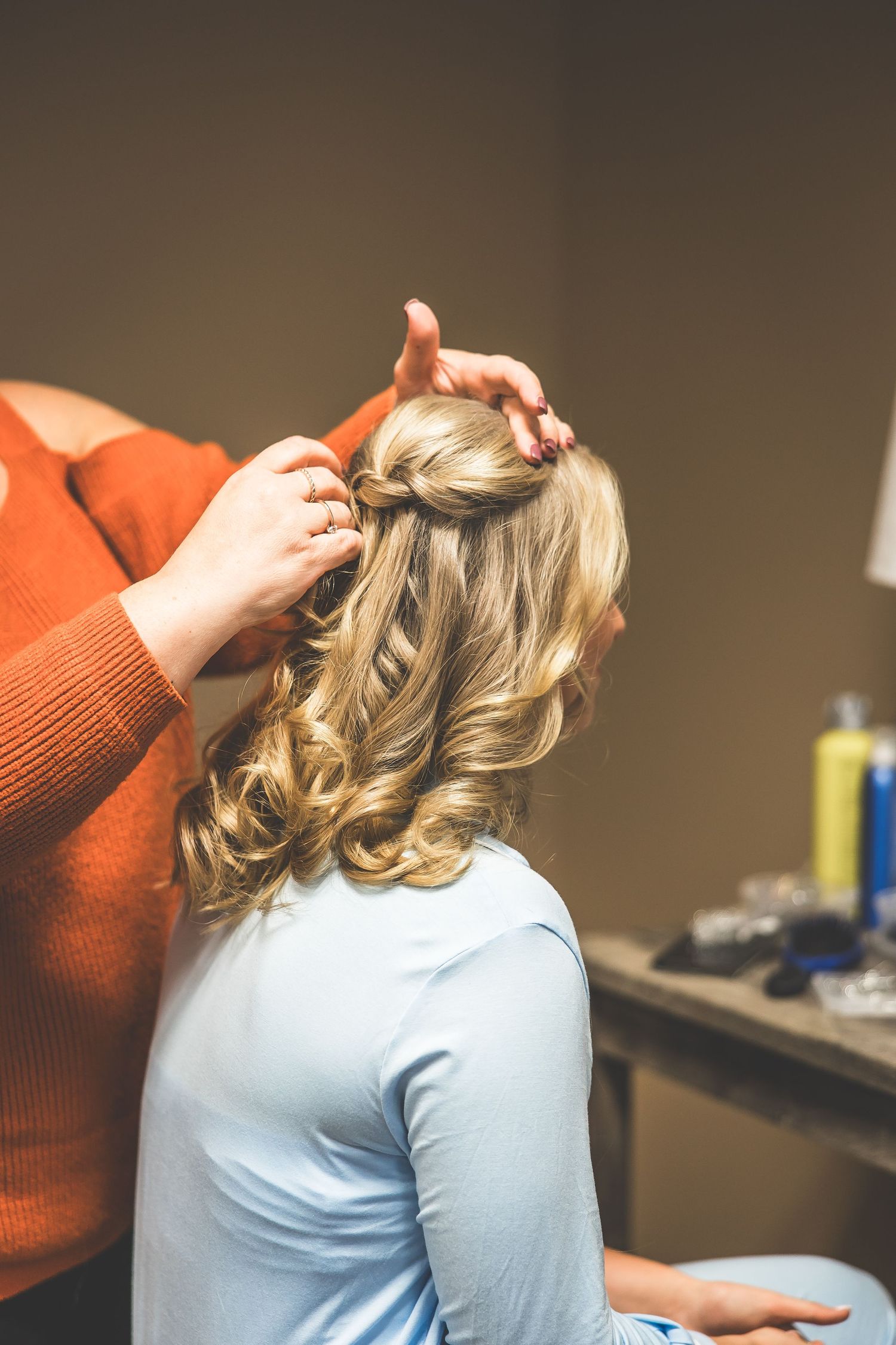 Hairstylist creates elegant curls during bridal preparation.