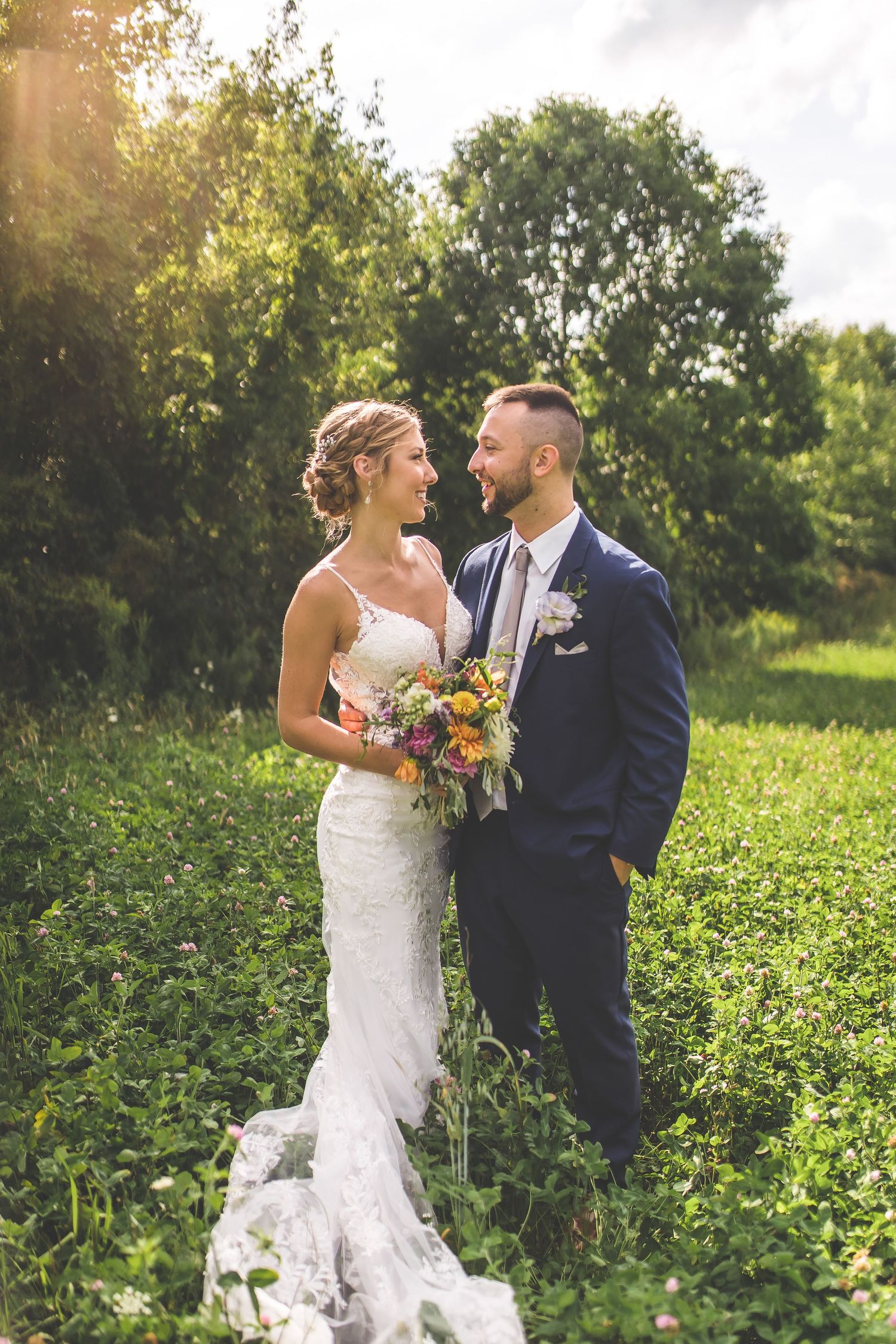 A romantic wedding photoshoot in a lush green field with rolling hills in the background.