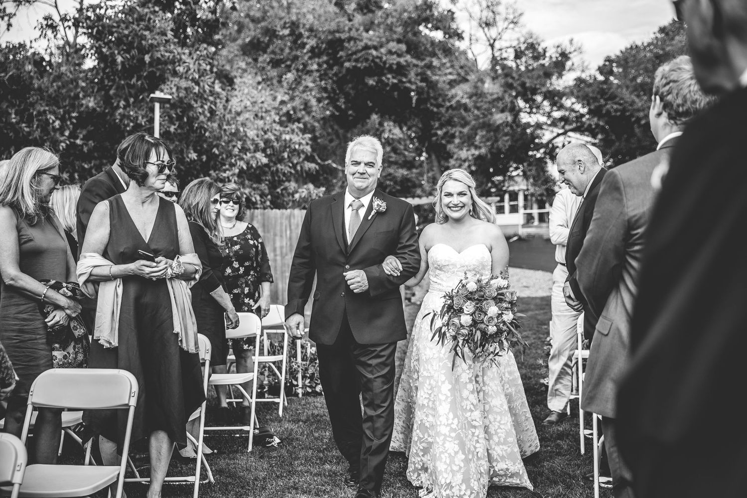 Wedding guests greet and embrace each other during an outdoor ceremony reception.