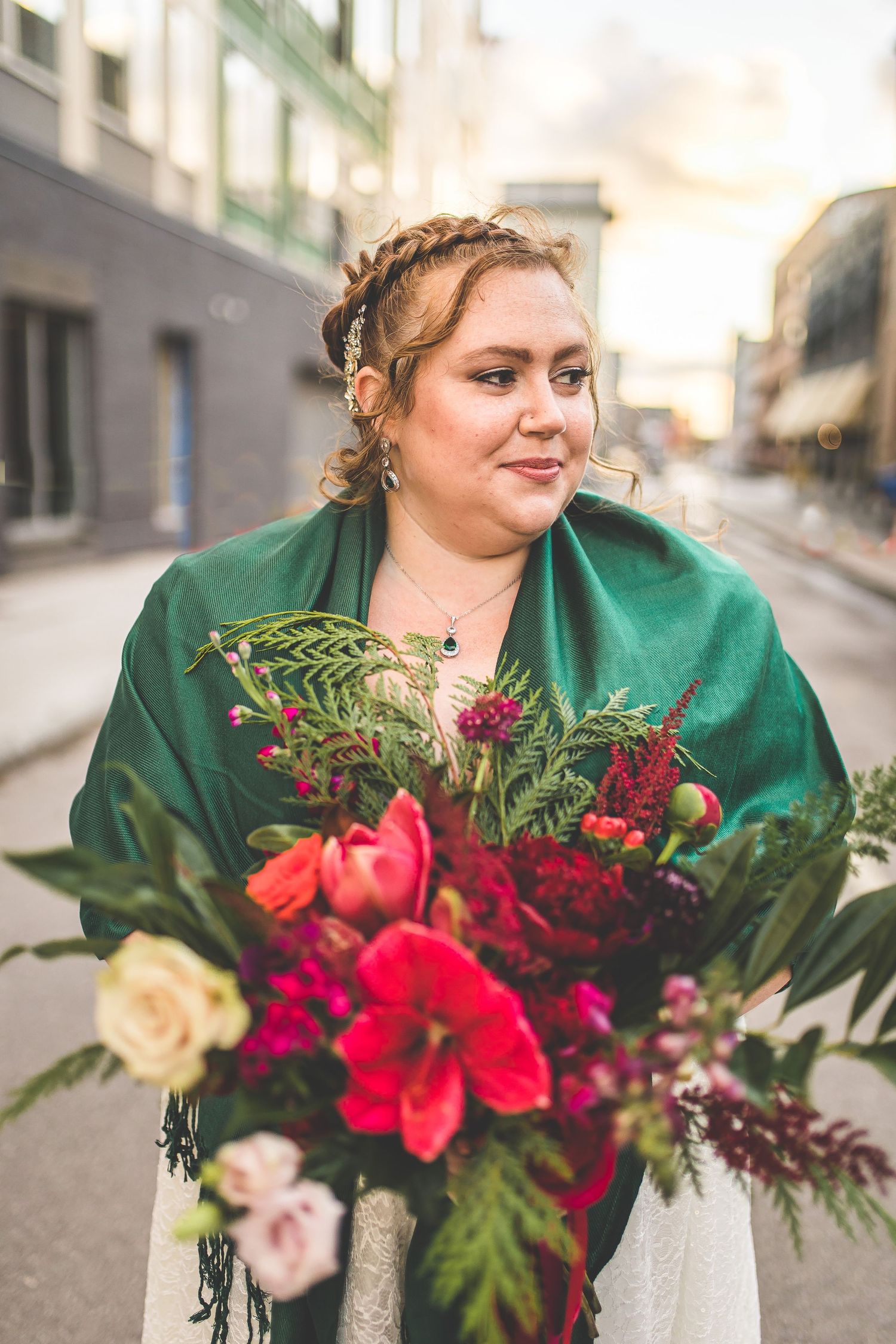 Close-up of lush red and burgundy wedding bouquet with tropical greenery.