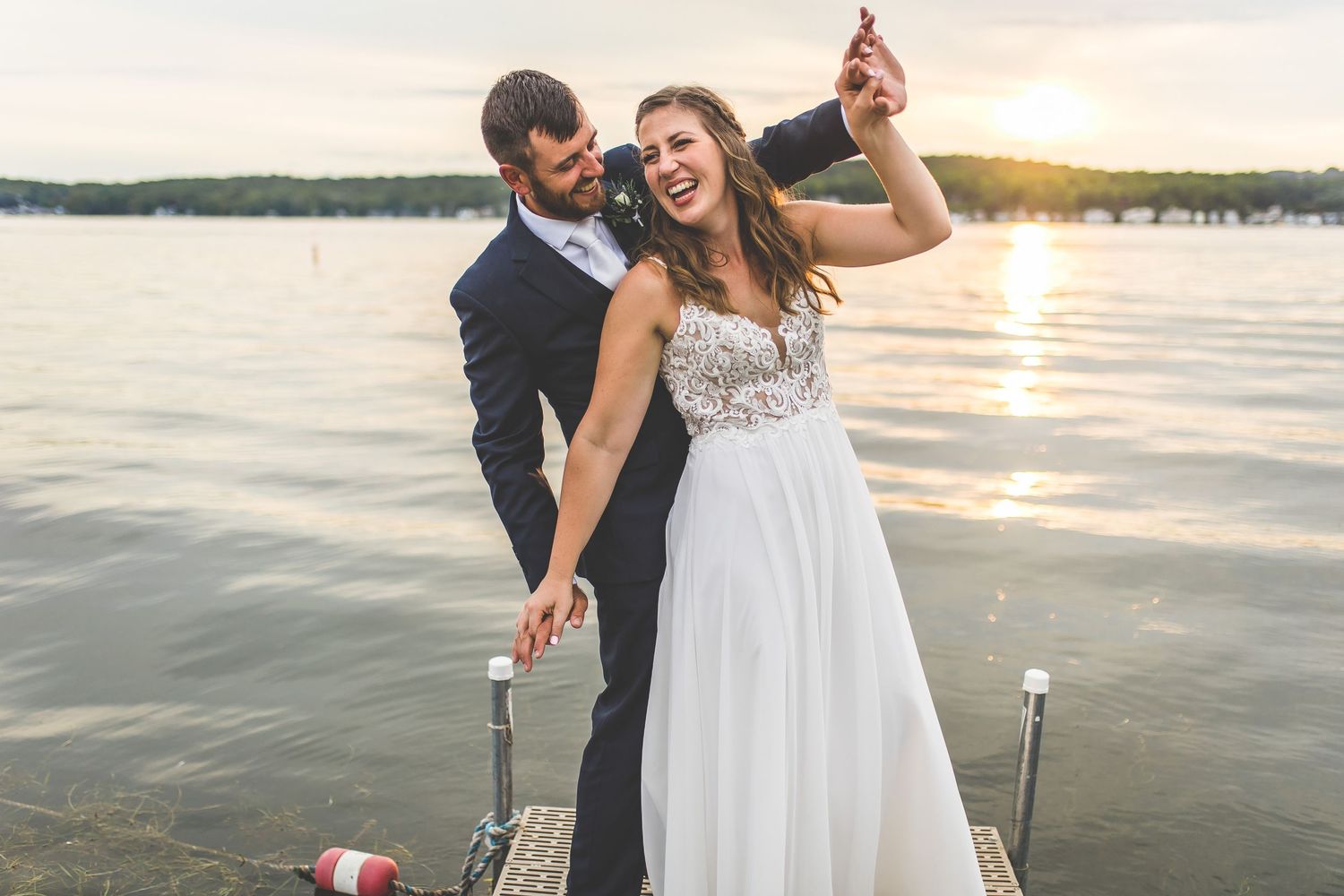 Wedding celebration on waterfront dock with scenic lake views at dusk.