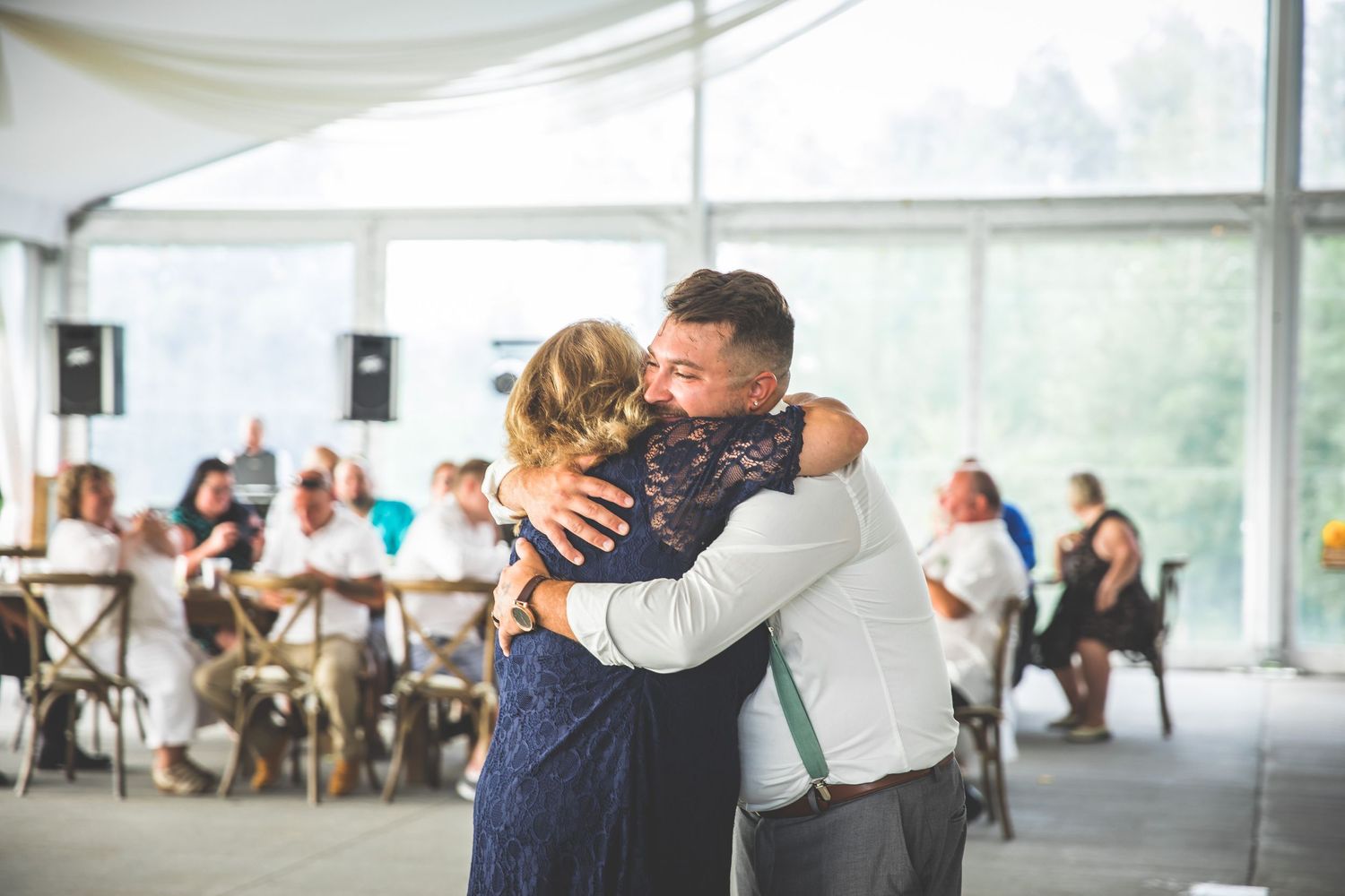 An intimate dance moment captured at a wedding reception with guests seated in the background.