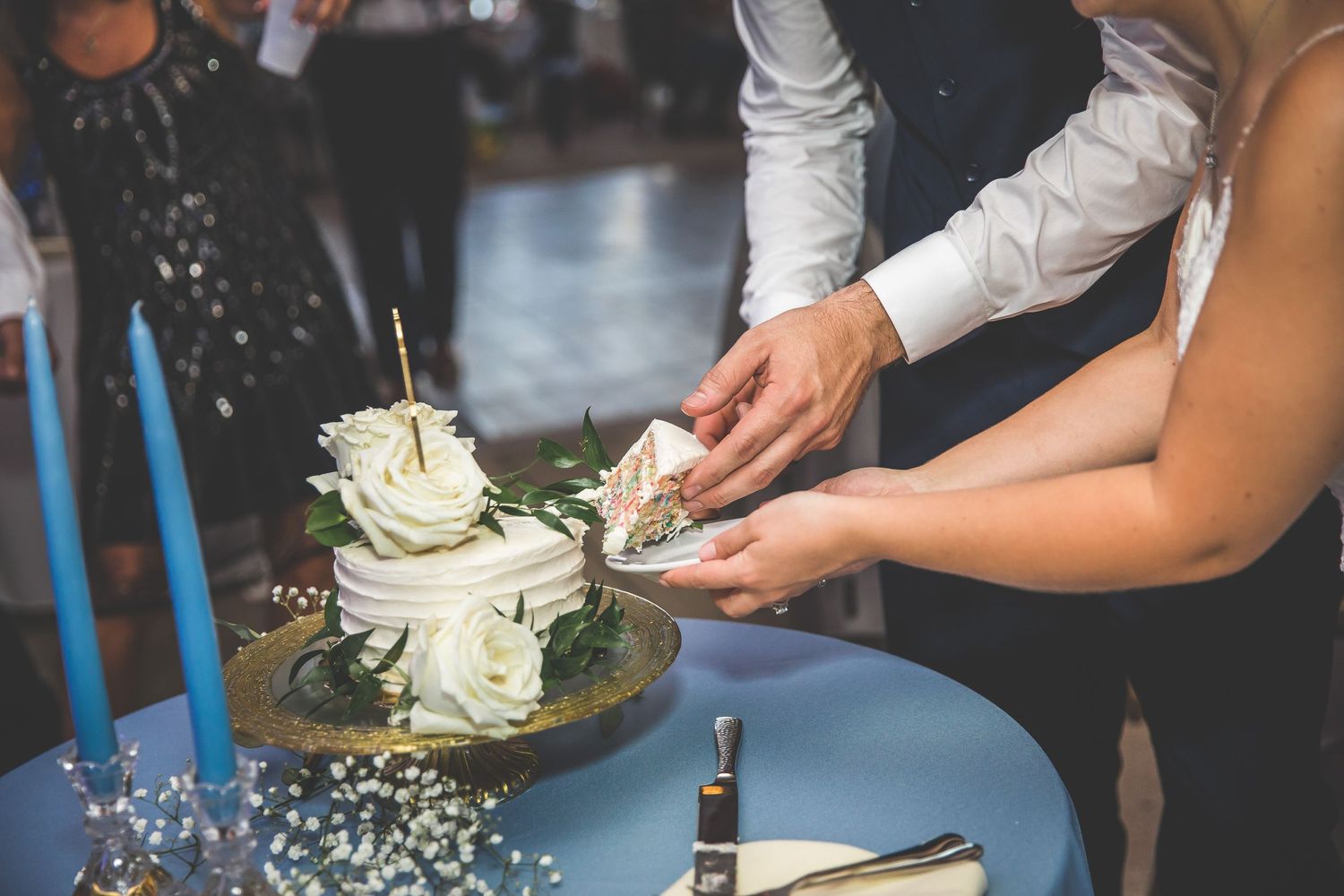 Wedding guests dancing and celebrating on a dance floor under string lights at an evening reception.