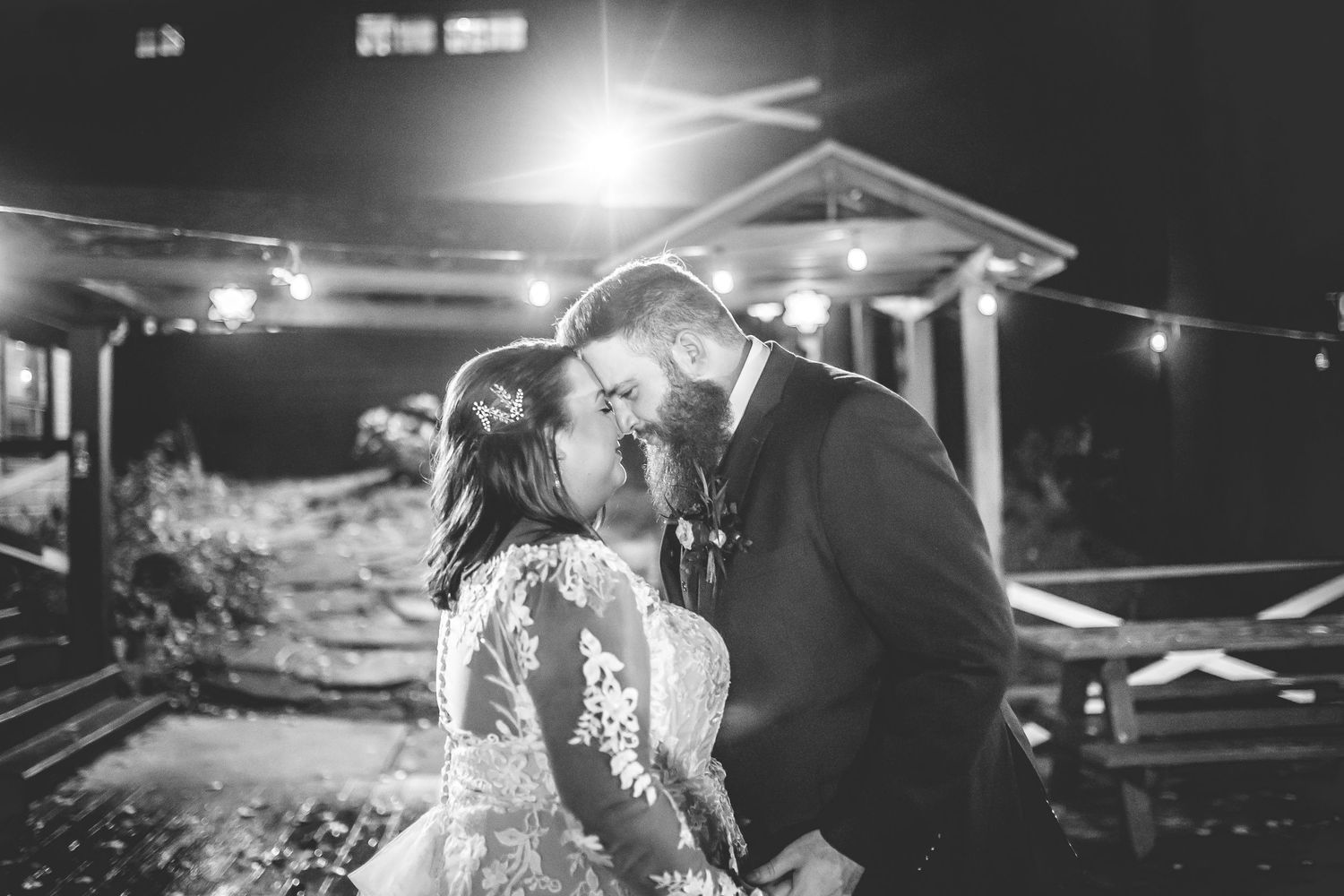 Night wedding reception scene with string lights creating romantic ambiance outdoors.