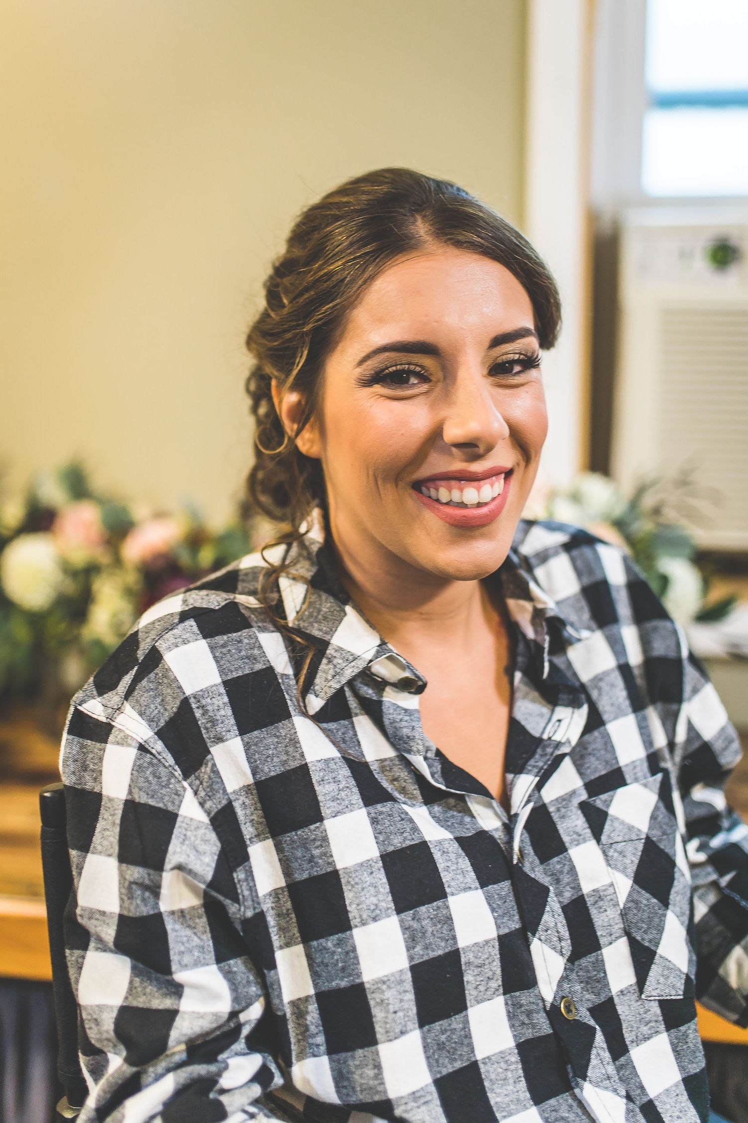 Person wearing black and white buffalo plaid shirt smiling in natural window light.