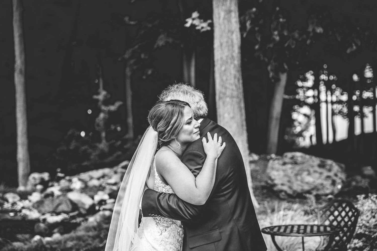 Wedding couple embraces during their first look in a wooded outdoor setting.