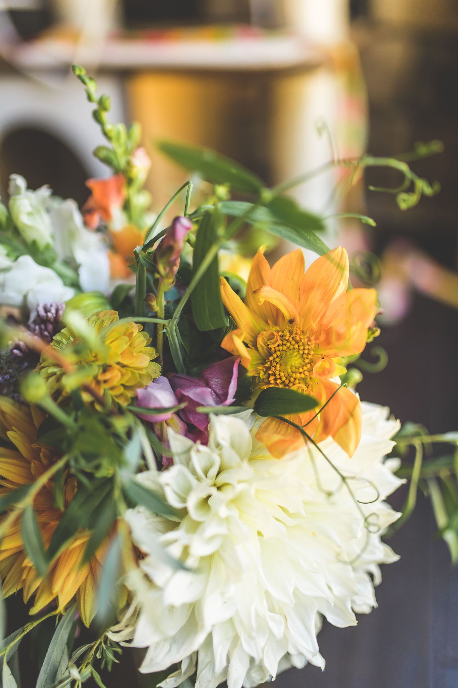 Colorful wedding bouquet featuring orange sunflowers, white chrysanthemums and purple wildflowers.
