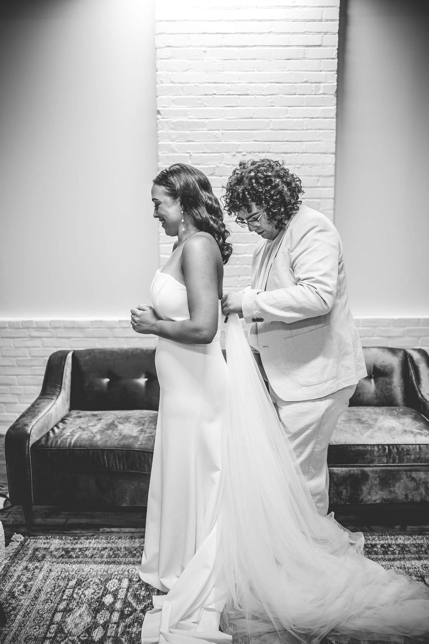Black and white photo of wedding dress movement against white brick wall.