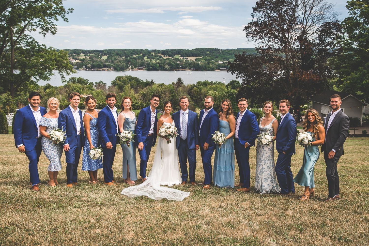 Panoramic view of wedding party lined up against scenic hillside backdrop.