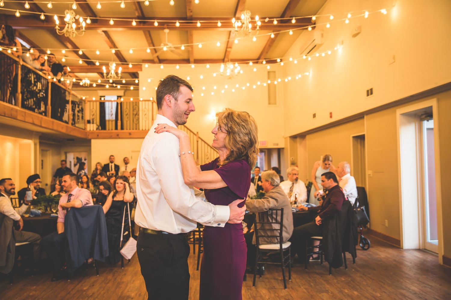 Wedding reception hall decorated with warm ambient lighting and string lights.