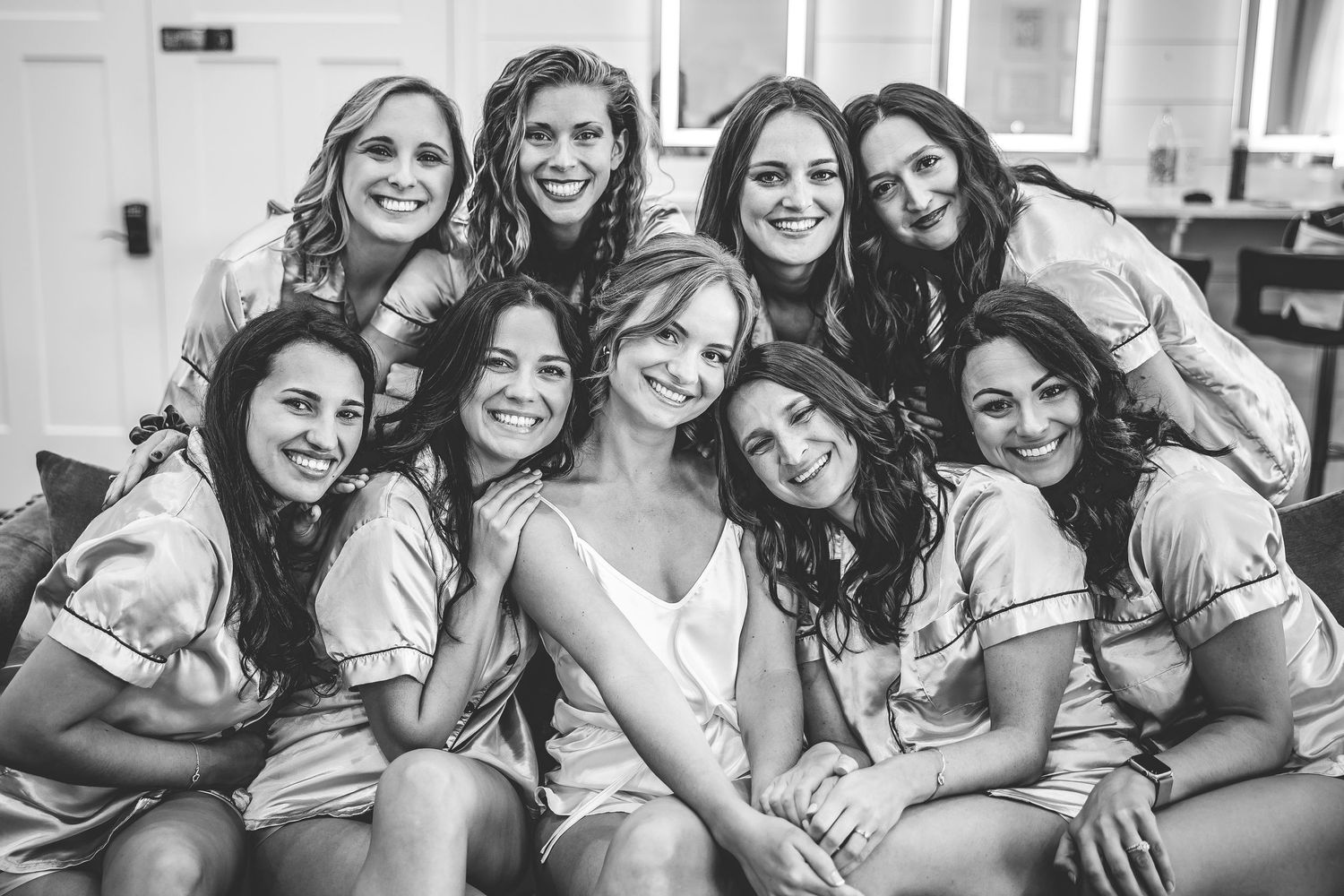 Black and white photo of wedding party members sharing a joyful moment together.