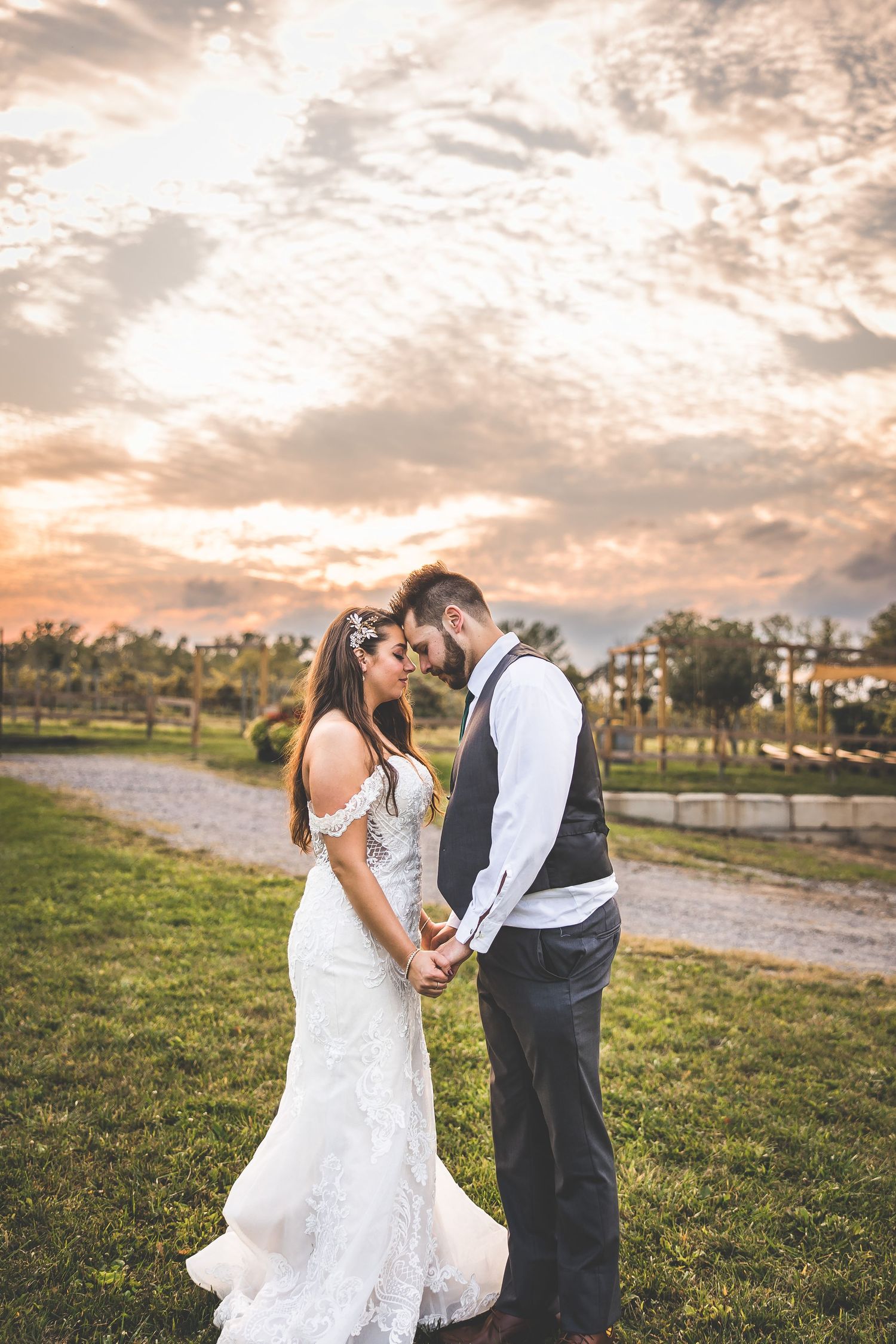 A romantic sunset wedding photo shoot in a grassy field with warm golden lighting.