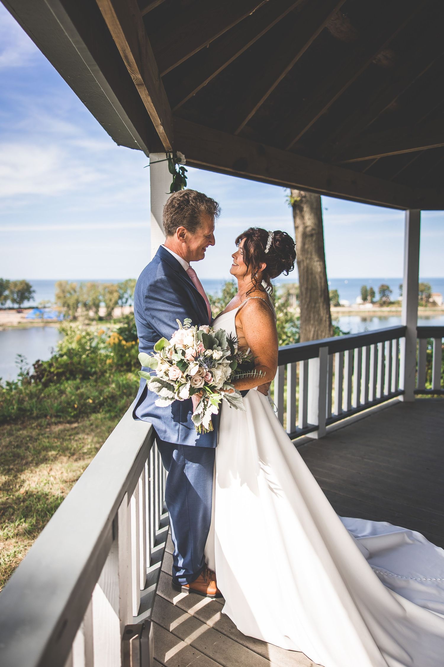 A couple shares an intimate moment on a covered porch during their wedding photoshoot.