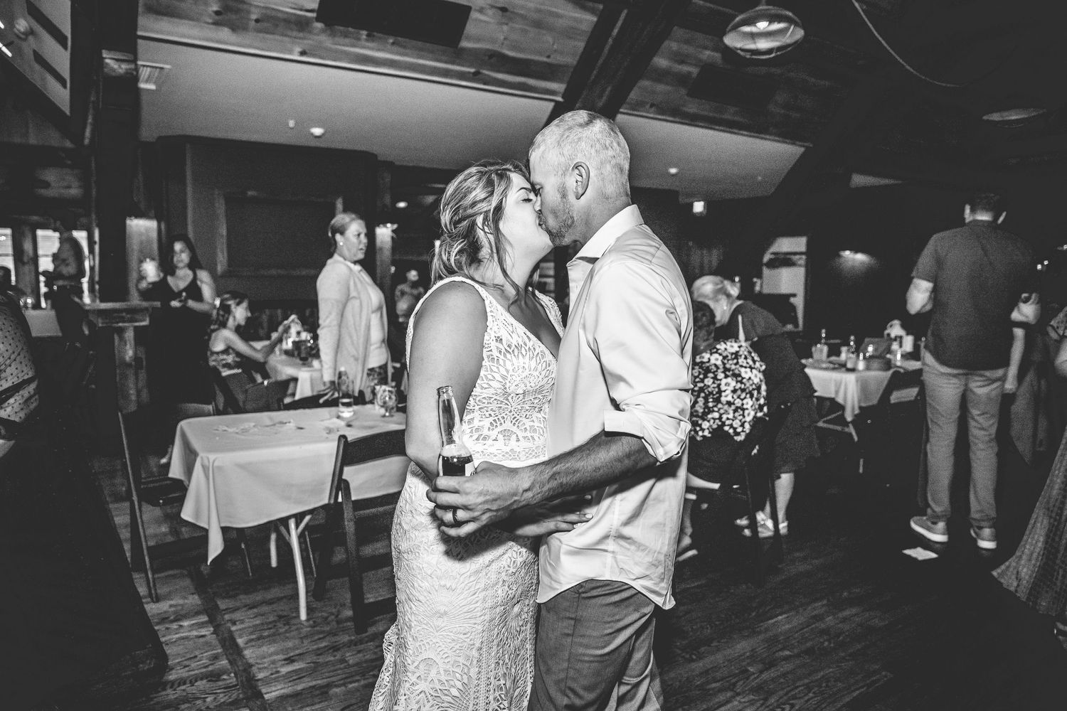 Black and white photo of wedding reception dance floor filled with celebrating guests.