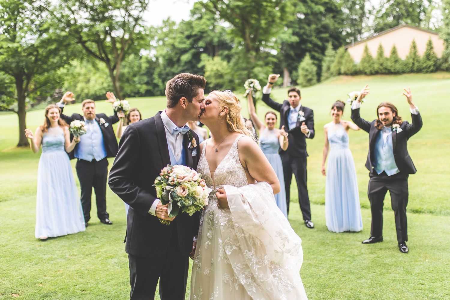 Wedding party celebrates with newlyweds in an outdoor garden ceremony.