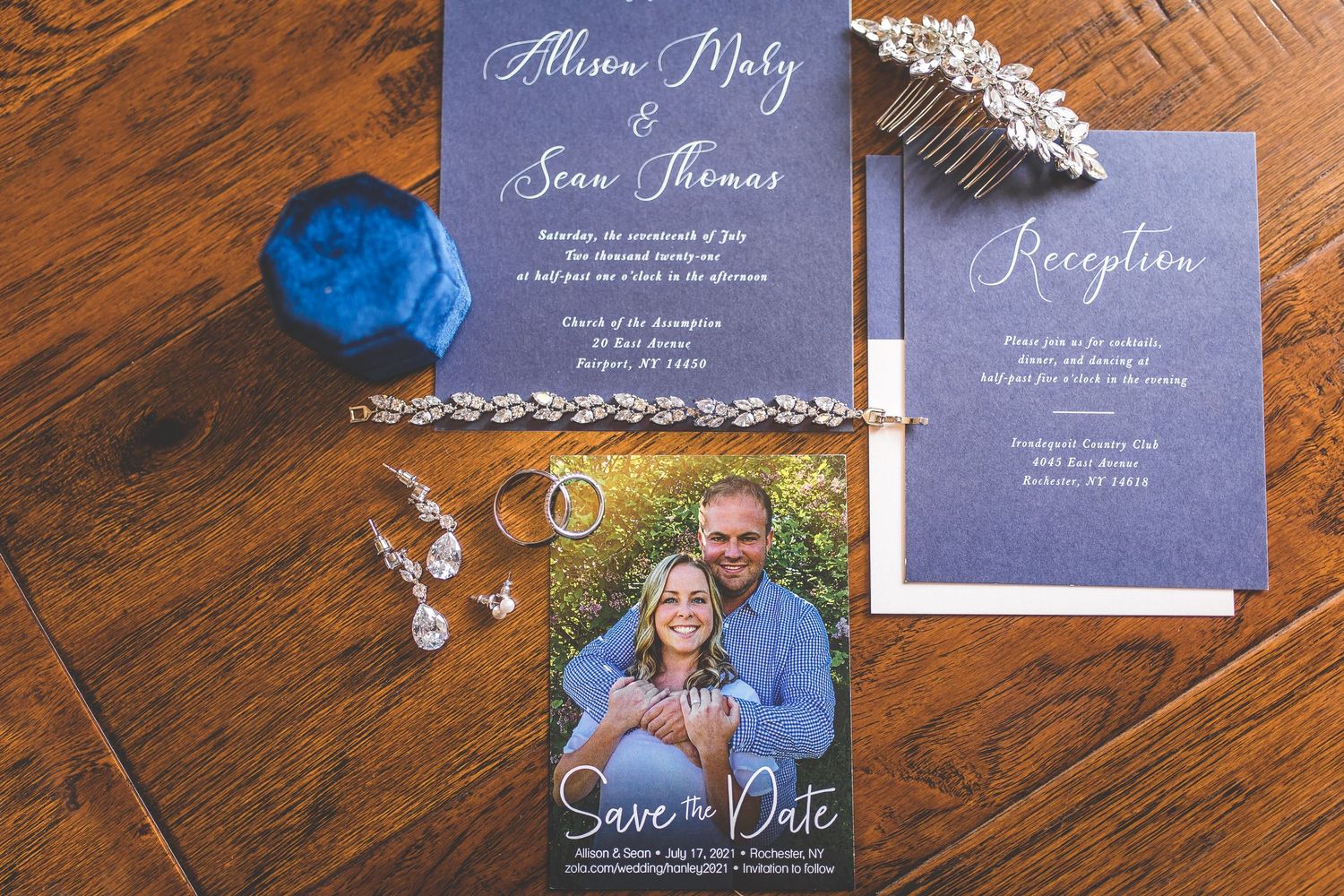 Wedding stationery suite in navy blue and white with decorative elements on wooden surface.