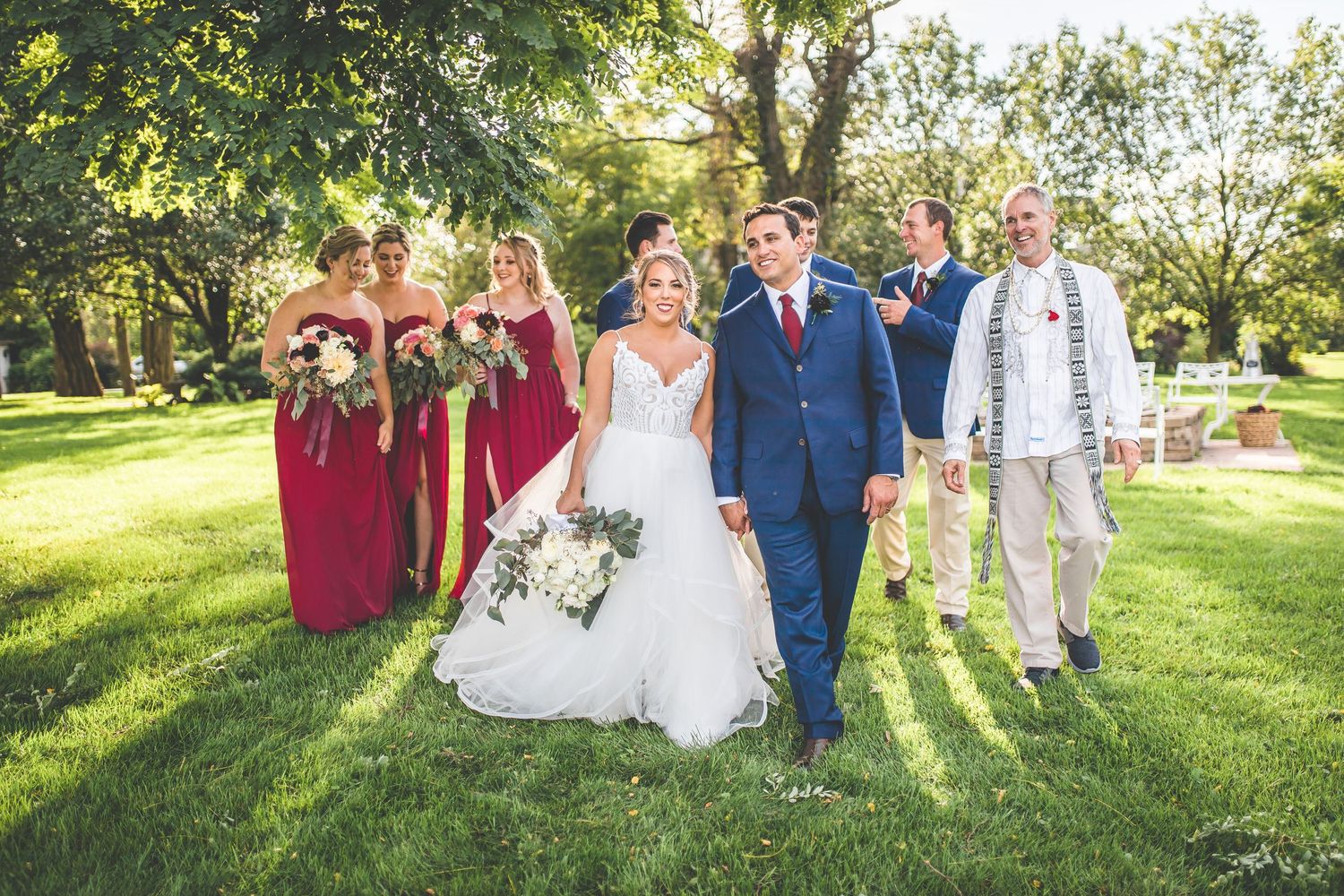 Wedding party poses for group photos on lush green lawn during summer celebration.