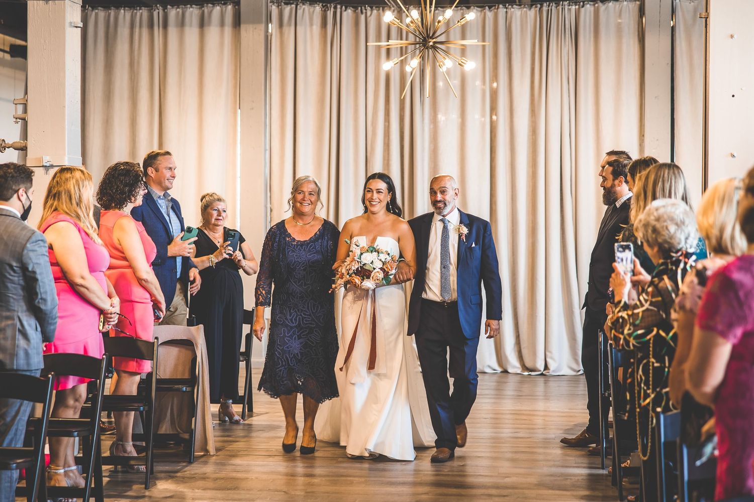 Wedding reception venue with guests mingling in an open space with draped curtains.