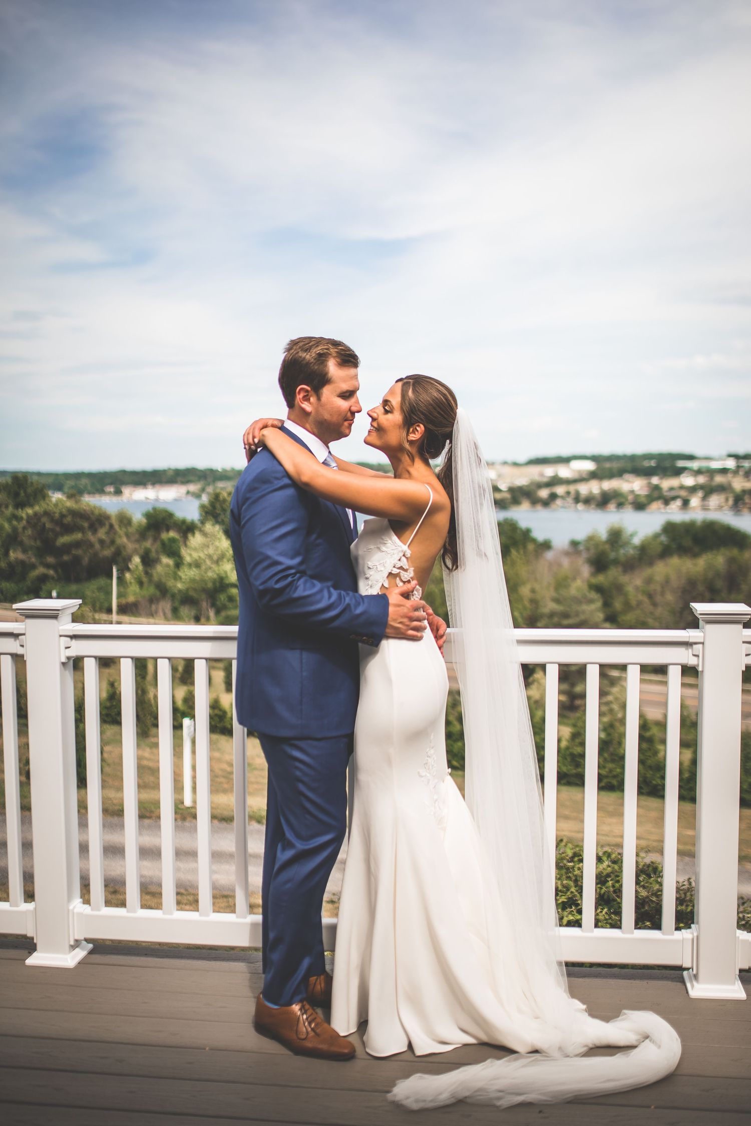Couple shares romantic moment on white deck overlooking waterfront view.
