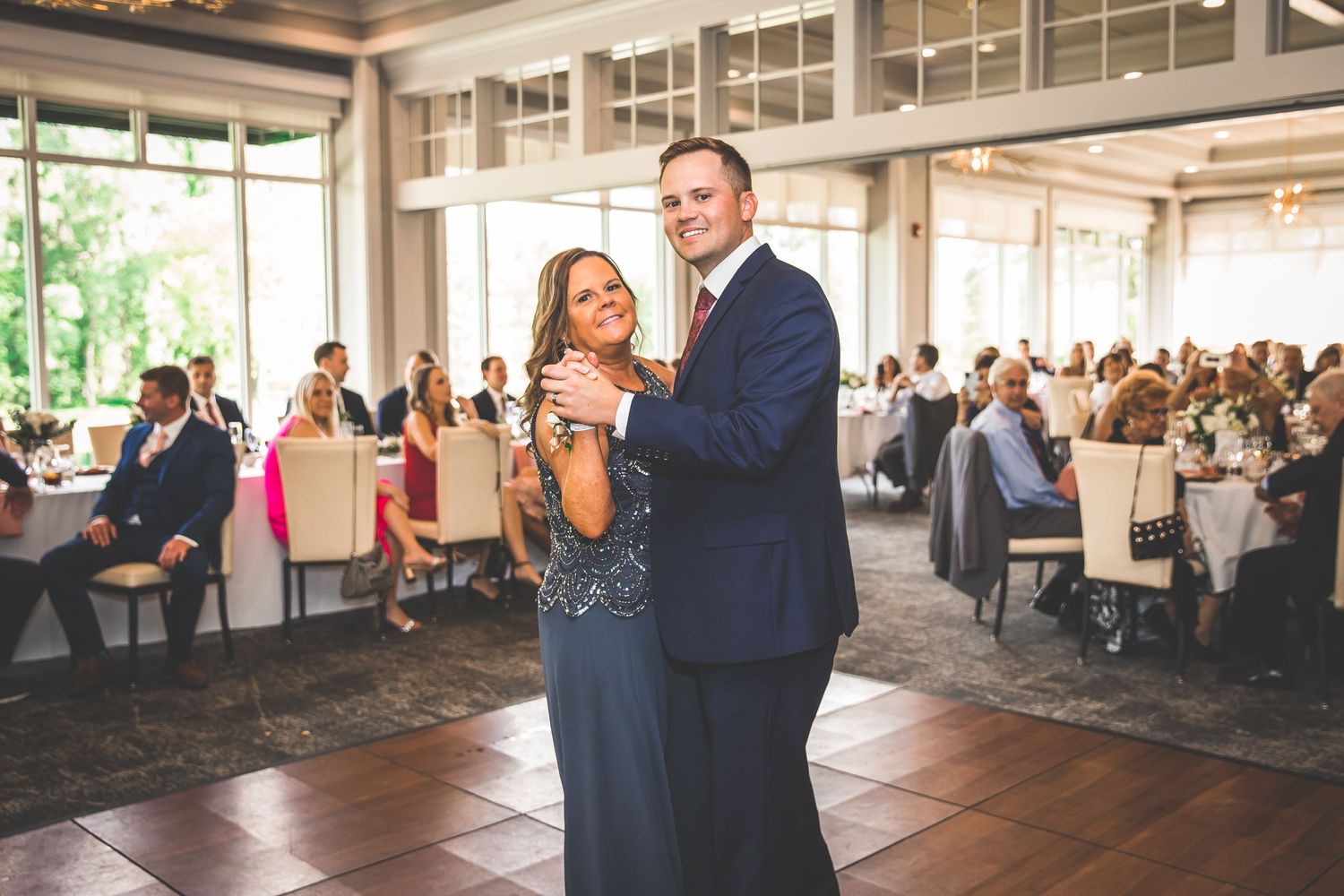 Wide angle shot of wedding reception space with natural lighting and dancing couple.