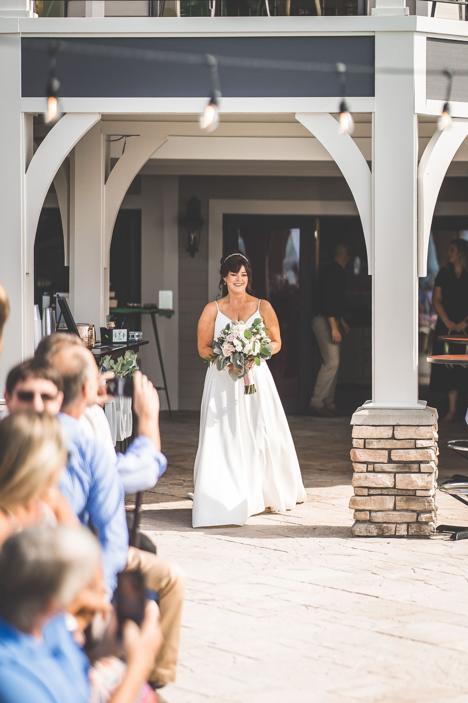 Elegant outdoor wedding venue with white columns and stone accents beside a pool area.