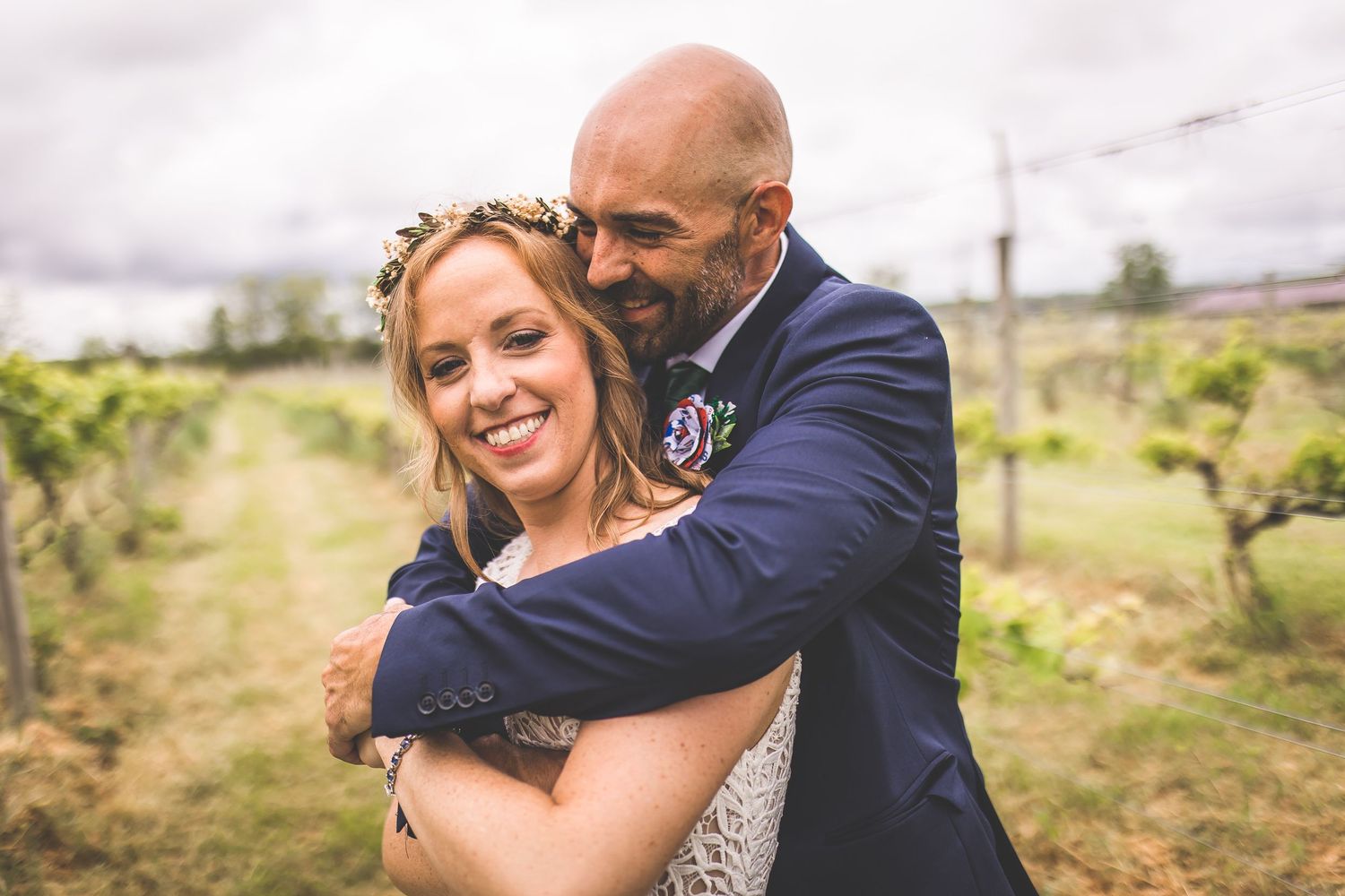 Happy couple embraces and laughs together during their vineyard wedding photoshoot.