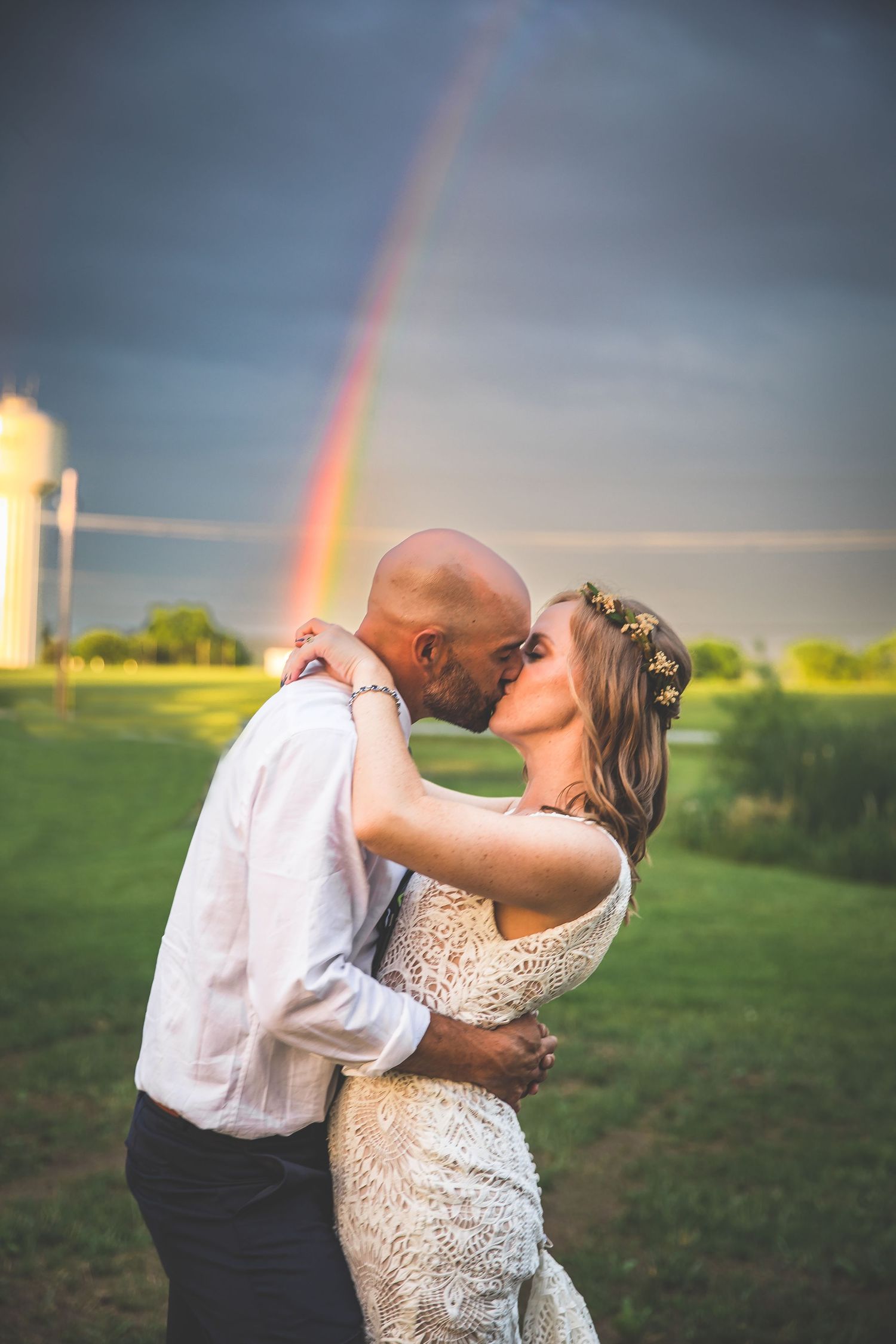A romantic dance moment captured against a dramatic sky with a rainbow in the background.