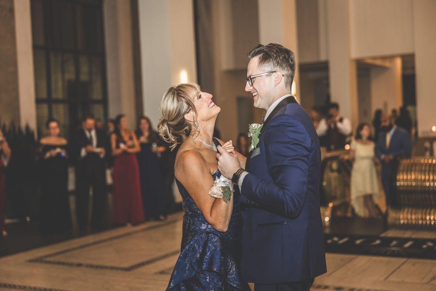Joyful couple dancing together at their wedding reception with guests in the background.