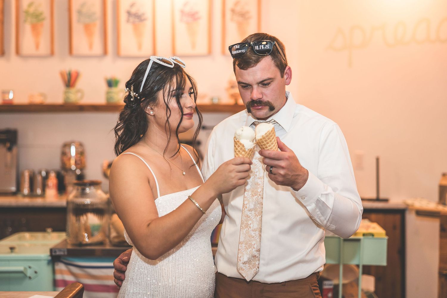 Couple sharing ice cream at a vintage-style ice cream parlor with peach-colored walls.