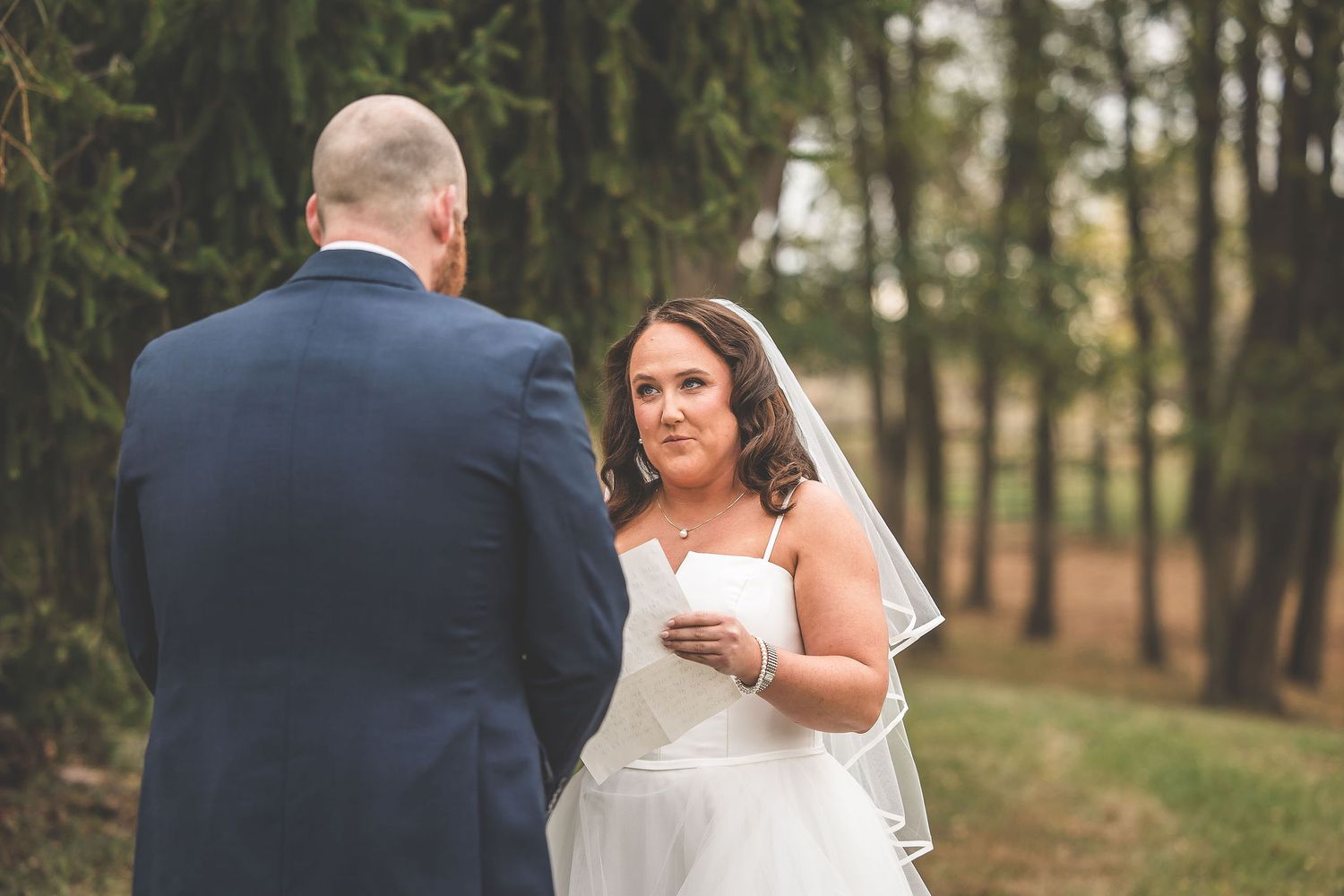 A couple exchanges vows during an intimate outdoor wedding ceremony surrounded by evergreen trees.