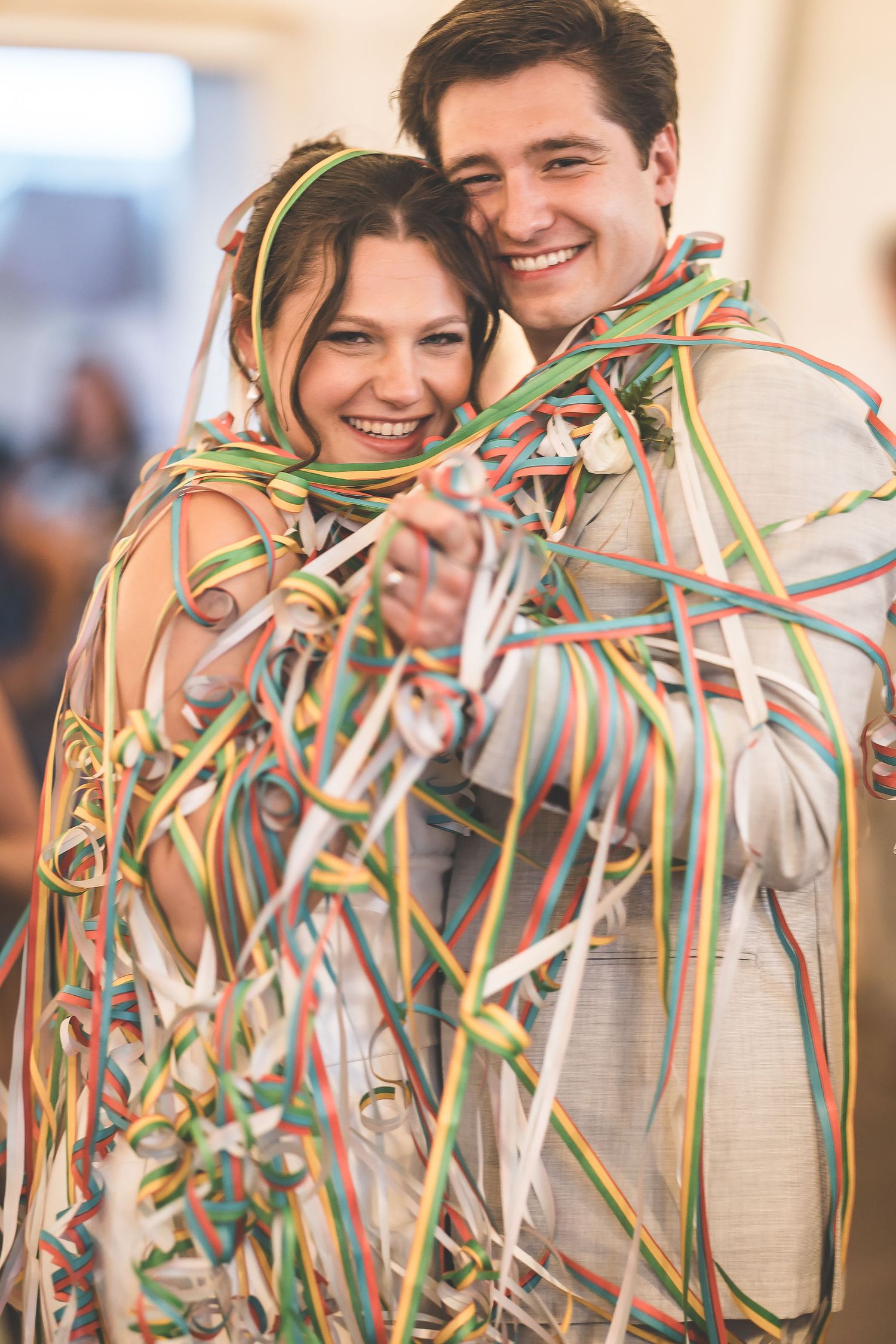Joyful celebration with colorful streamers and ribbons at an indoor wedding reception.
