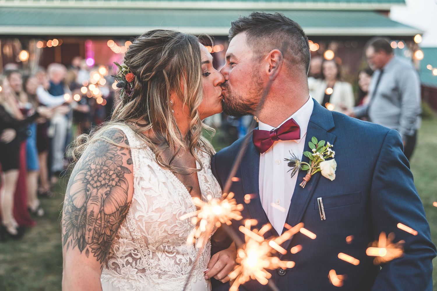 Romantic wedding couple portraits with sparklers creating magical light trails during sunset celebration.