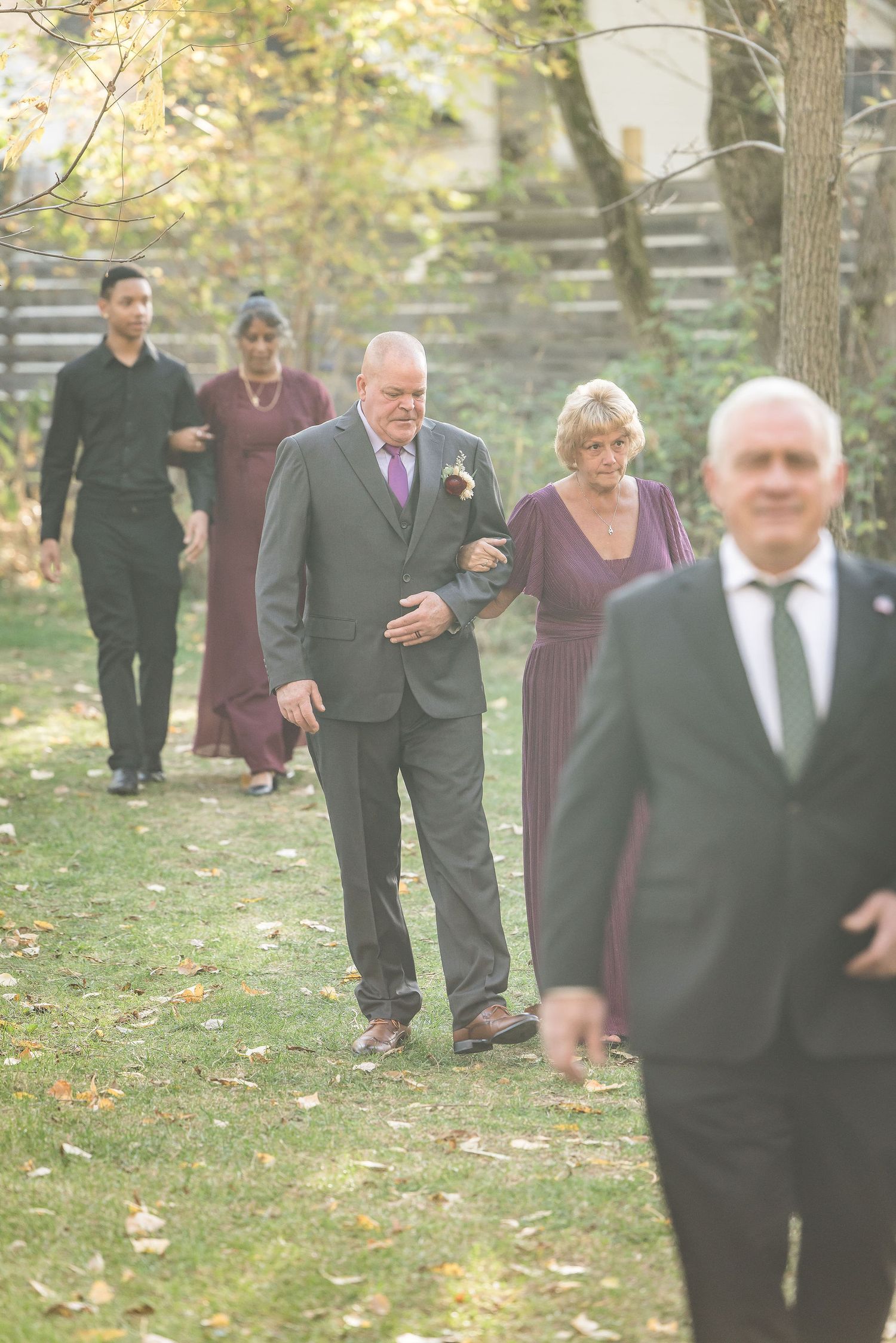 Wedding guests walking along a garden path during an outdoor ceremony.